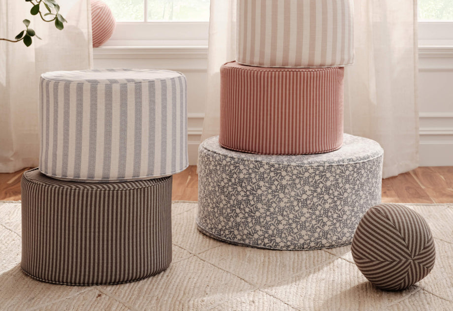 Set of round fabric ottomans in various patterns and colors on a light wooden floor.