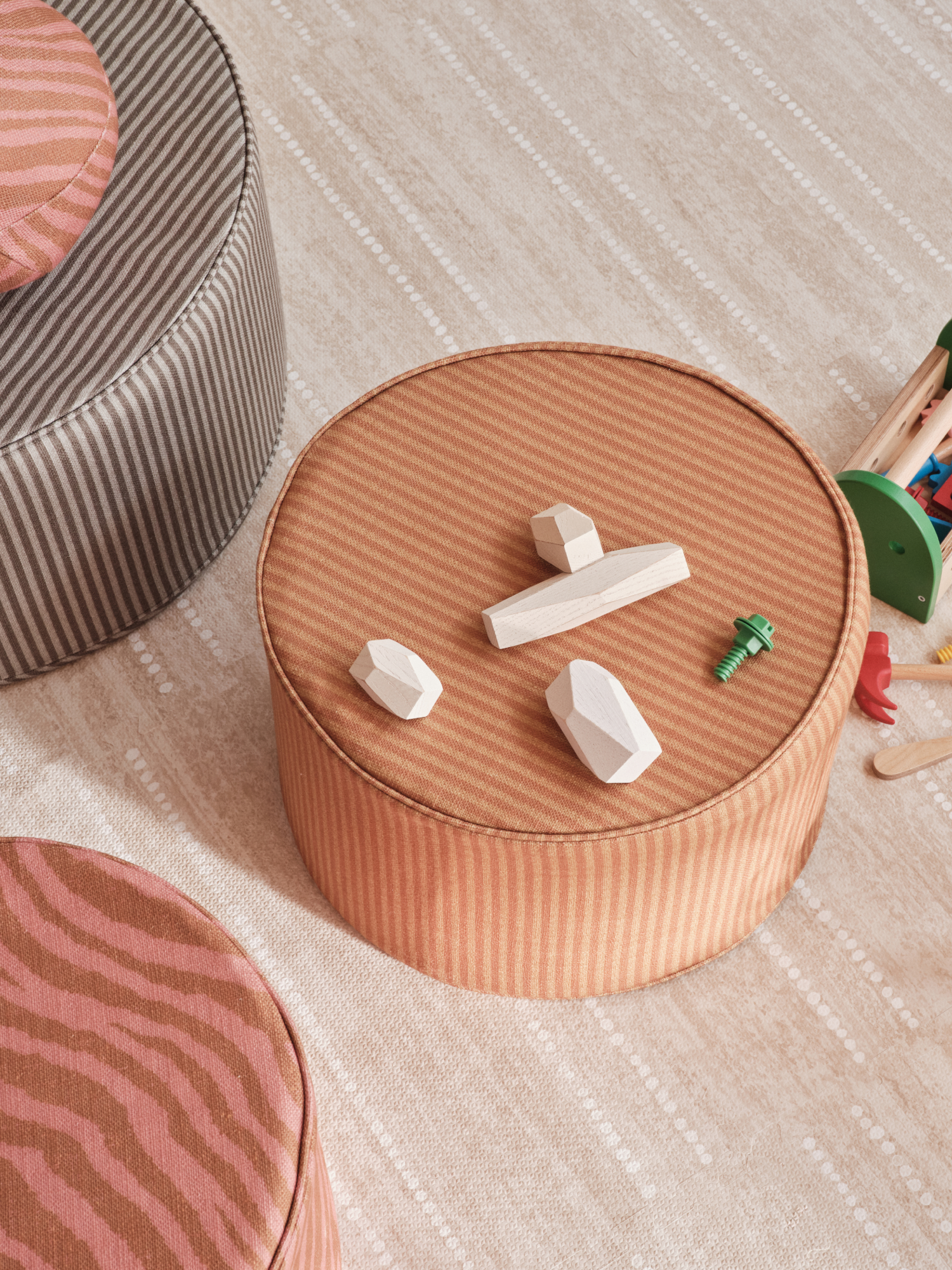 Toys spread on a round, striped ottoman and play mat