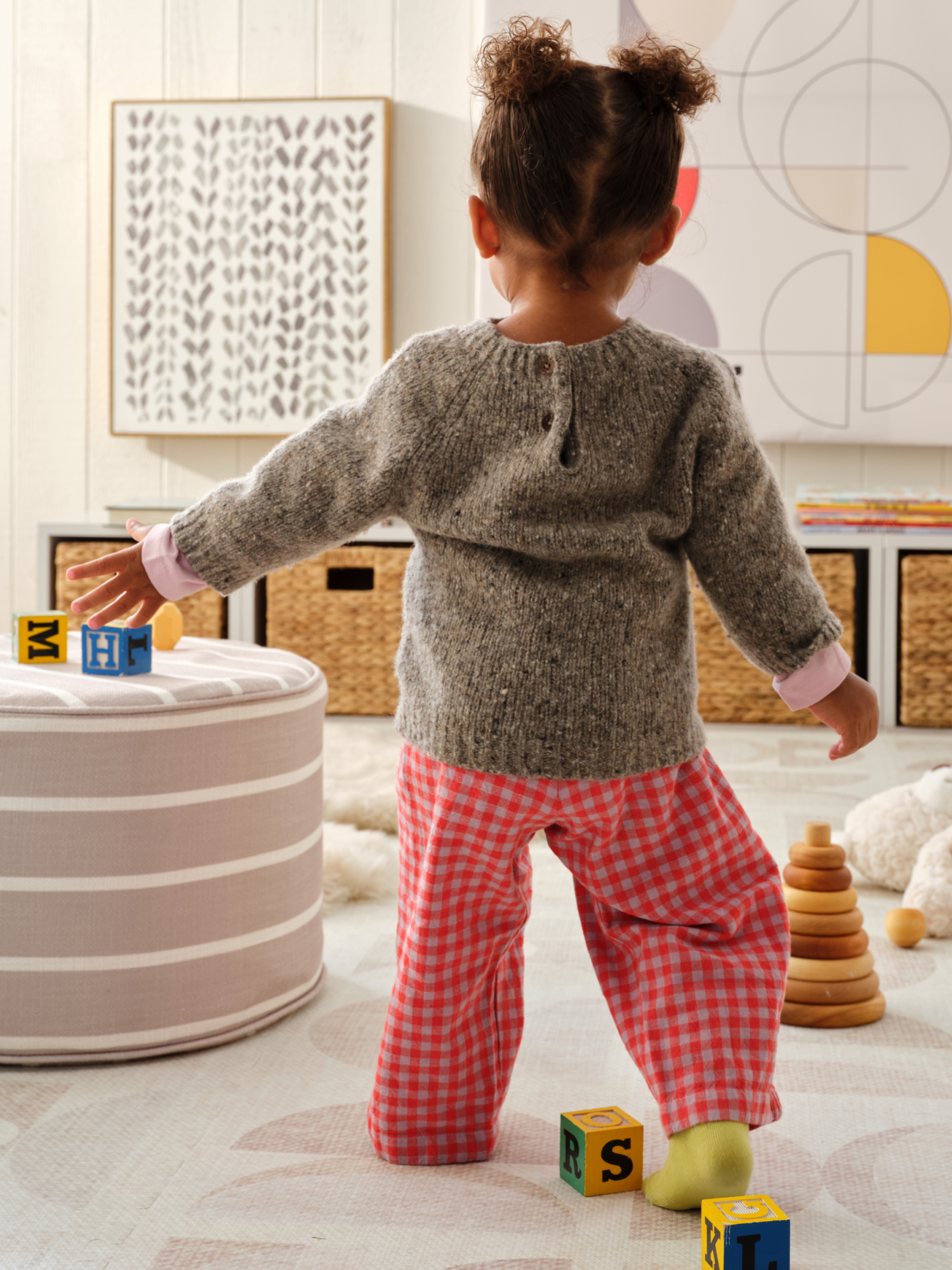 Child playing with blocks in a room with an ottoman and play mat