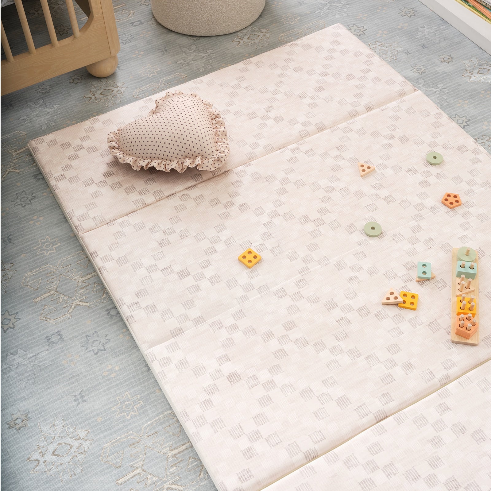 Baby play mat with toys and a heart-shaped pillow on a light blue floor.