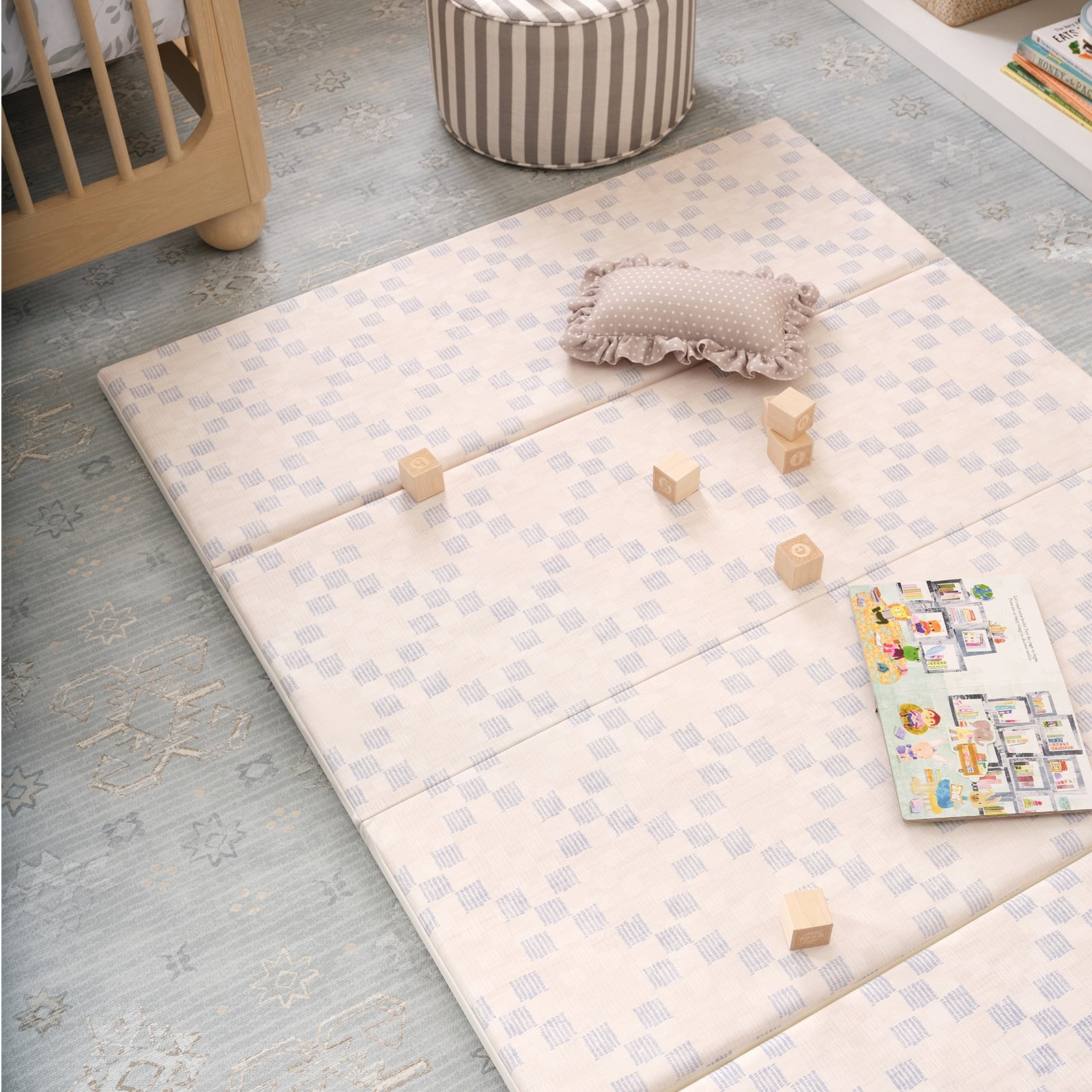 Children's play area with a cushioned mat, wooden blocks, and a book on a light blue play mat.