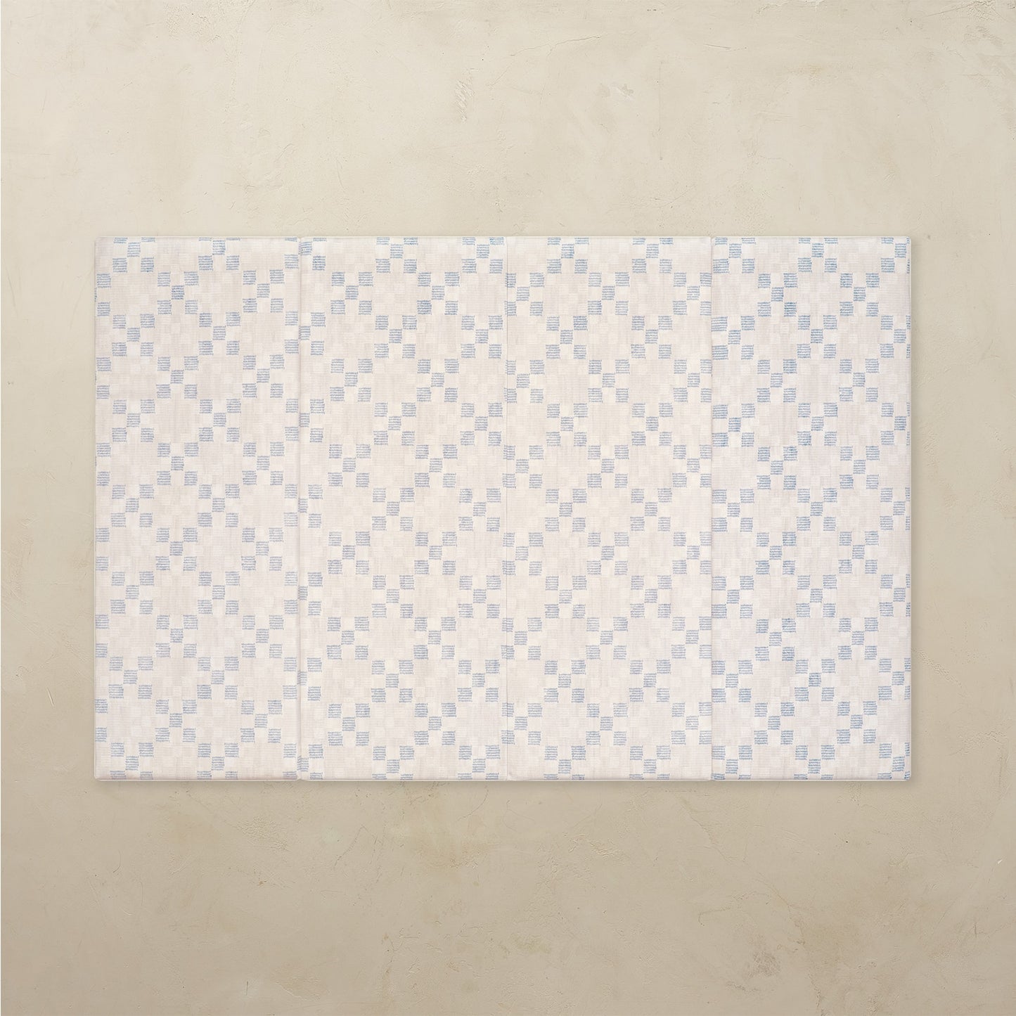Patterned tumbling mat with blue and white design on a beige background