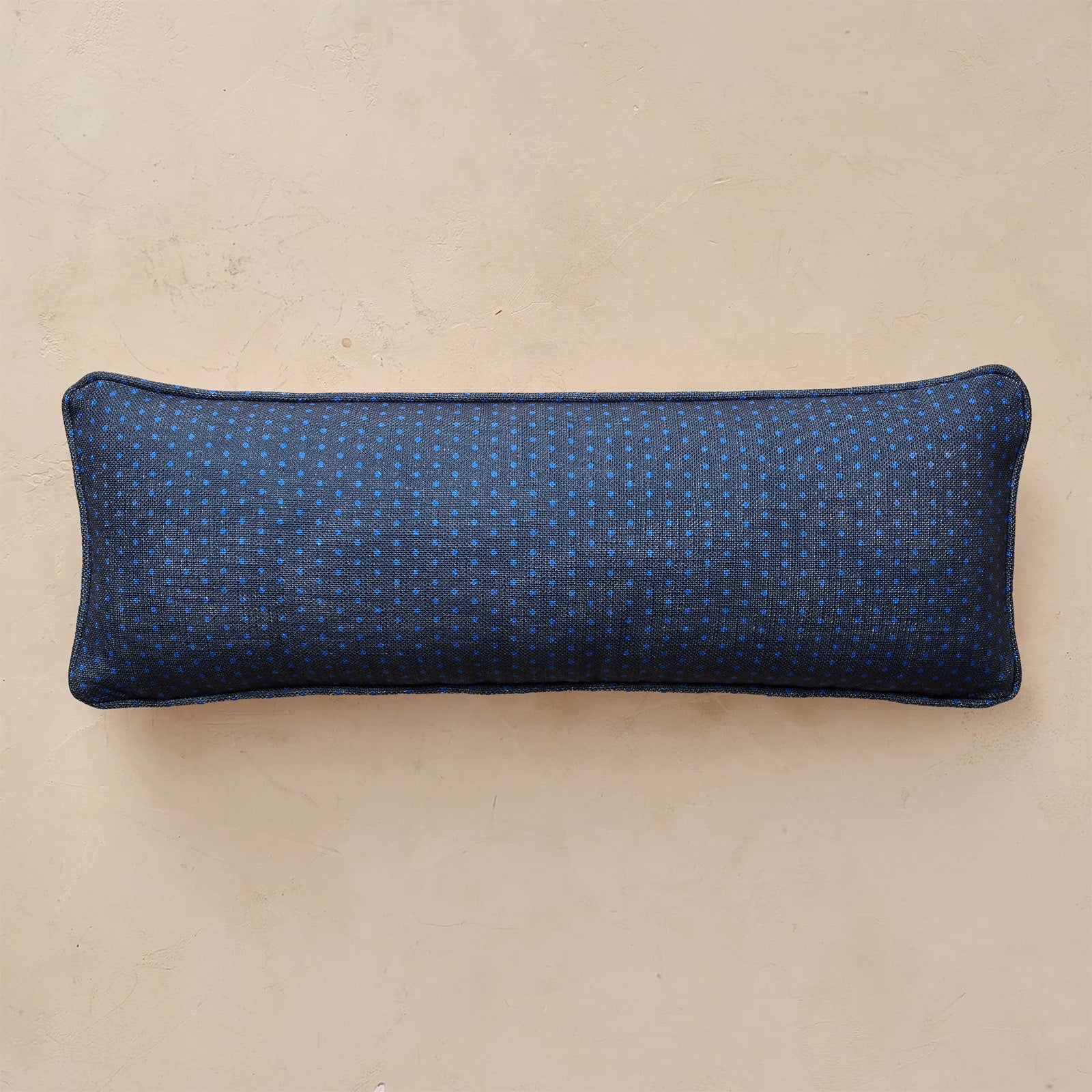 A rectangular lumbar pillow with a dark blue and teal geometric pattern, displayed horizontally against a neutral beige background.