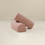 Two pink boucle armrests placed on a flat surface, one upright and one lying down, showcasing their texture and color.