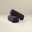 Two cylindrical boucle armrests in navy blue color, placed on a neutral surface.