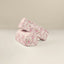 A pair of pink armrests with a multicolor floral vine print, placed on a white surface.