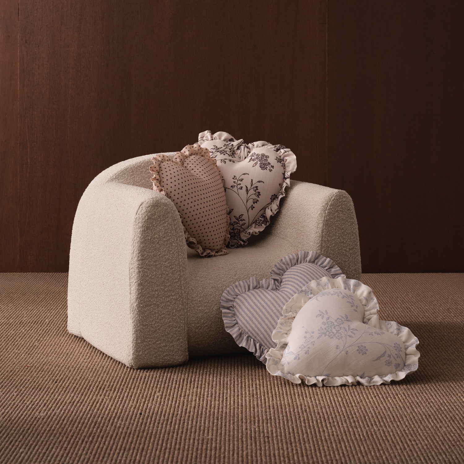 Small beige armchair with decorative pillows on a brown surface and background