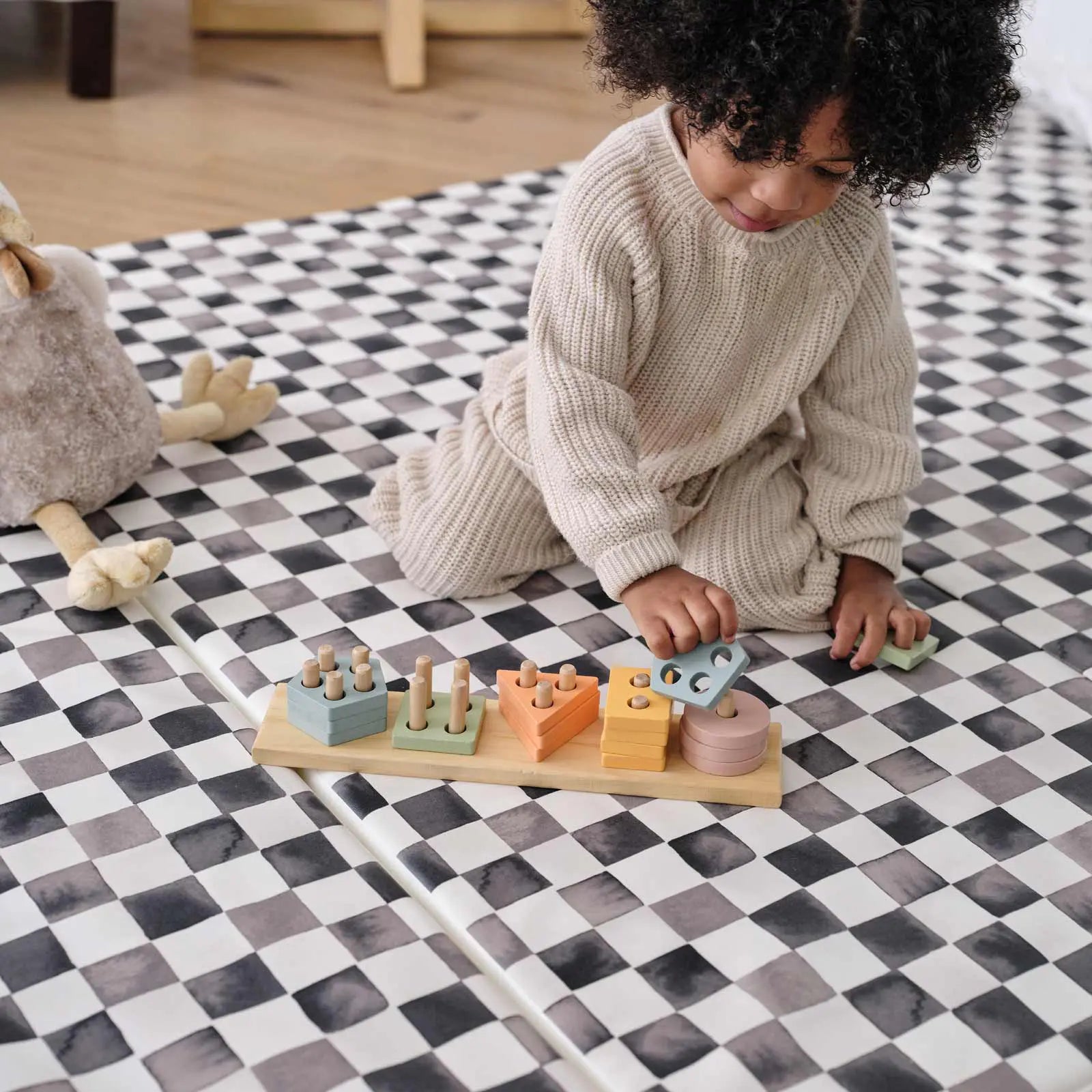 tuxedo black and white checker print tumbling mat with toddler playing with colorful wooden toy