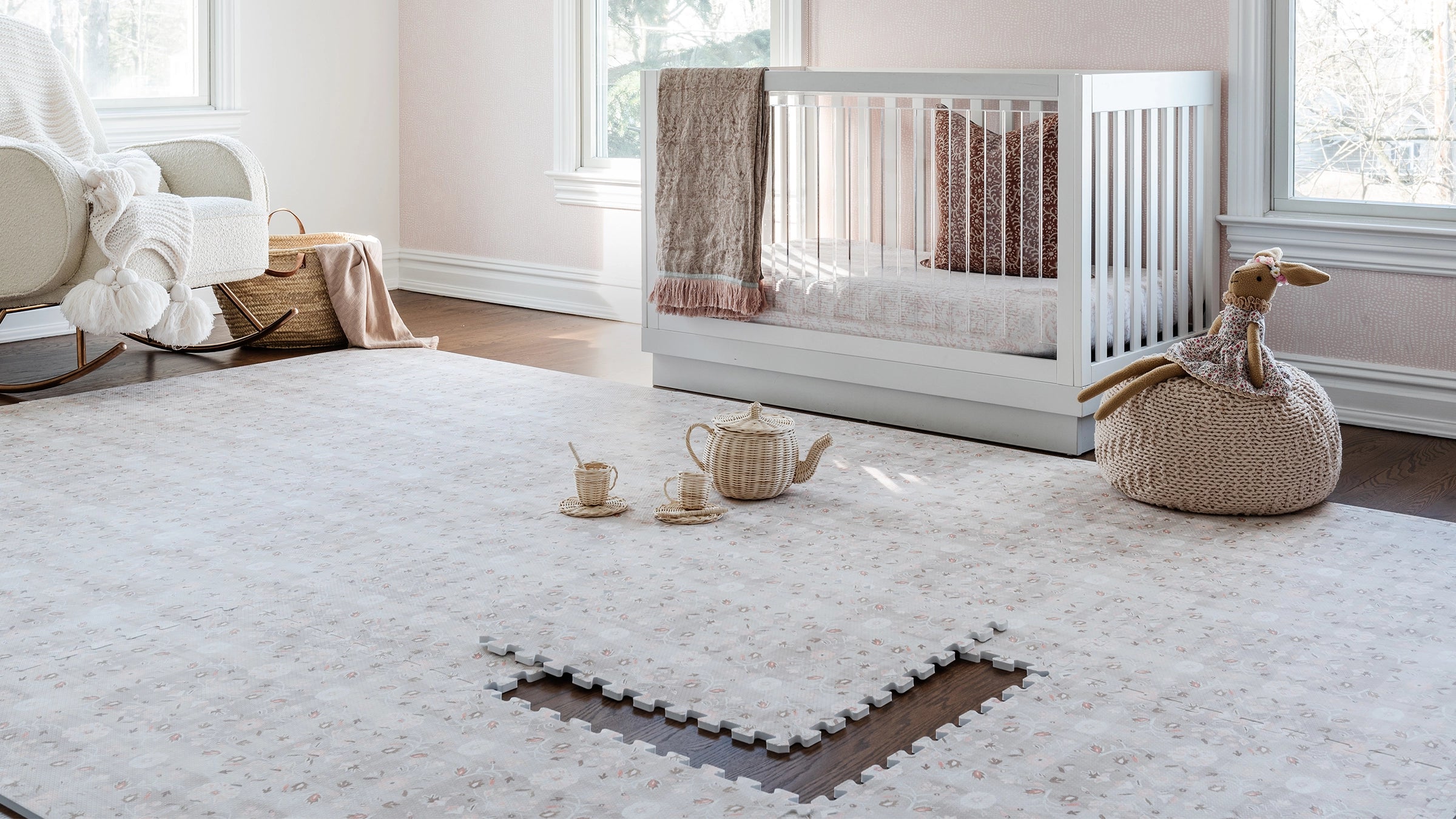 Linen beige and light pink floral pattern play mat shown in nursery with 1 tile exposed and wicker tea set on the mat