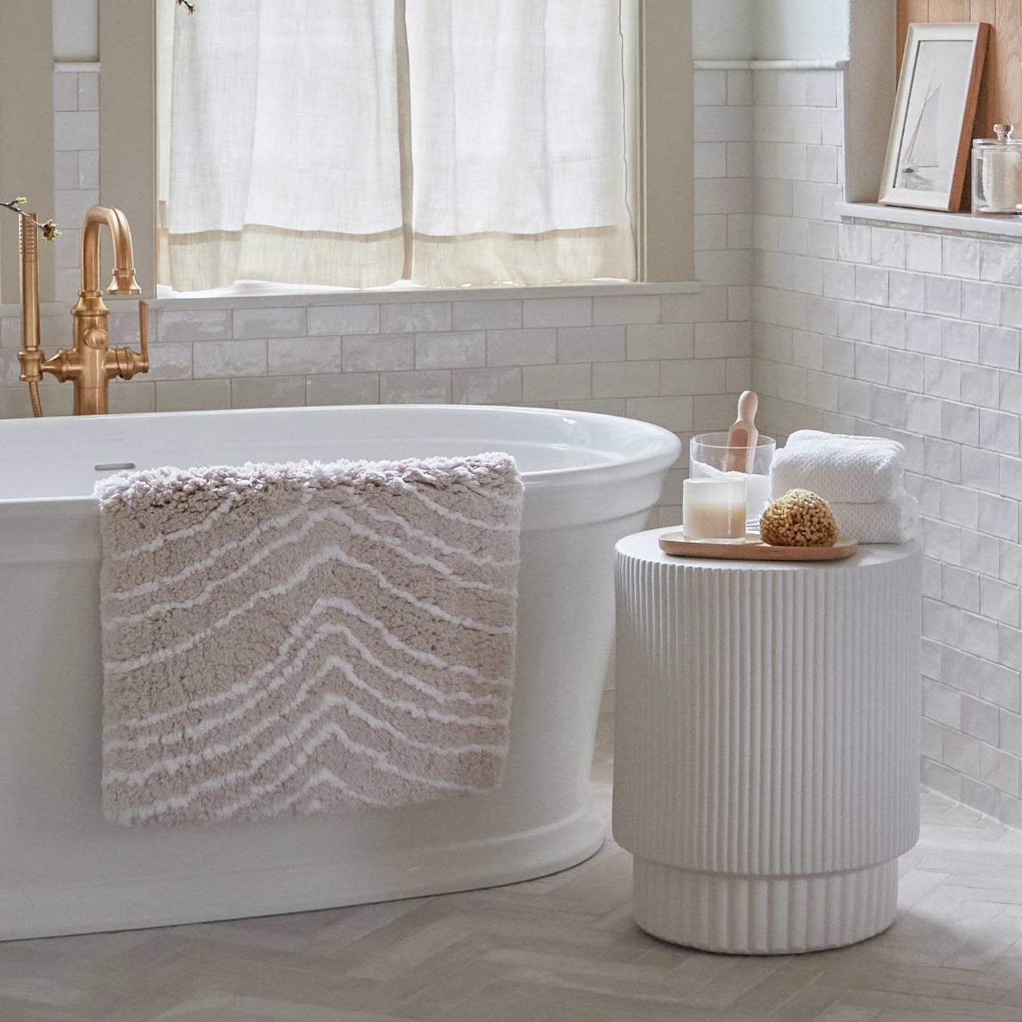 Zelda Shell beige zebra print bath math hanging over the side of a tub to dry with bath accessories on a side table  
