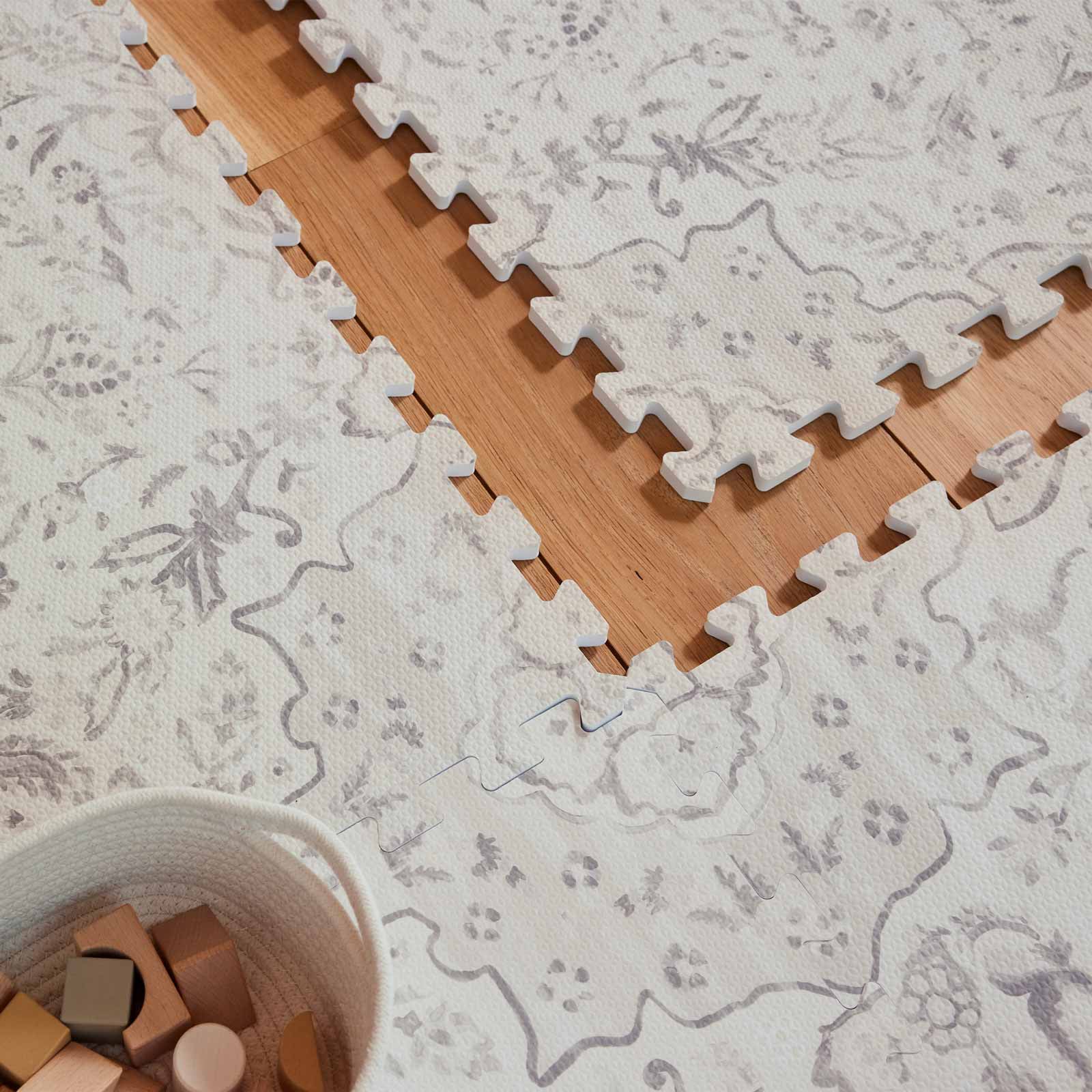 Emile latte neutral floral play mat shown up close with 1 tile exposed and a basket of wooden blocks