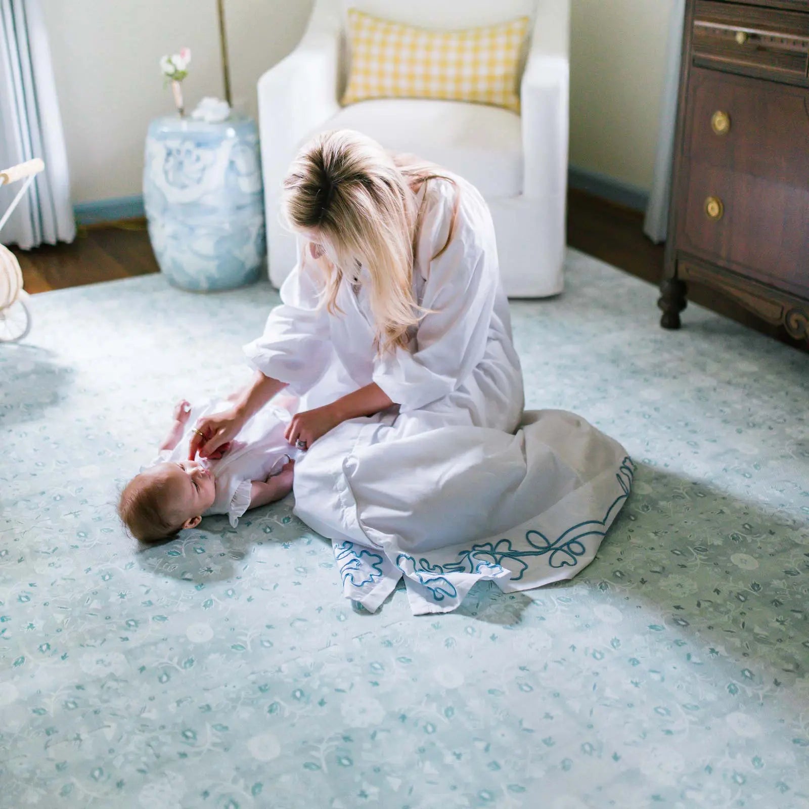 Powder blue floral pattern play mat shown in nursery with Mom playing with baby