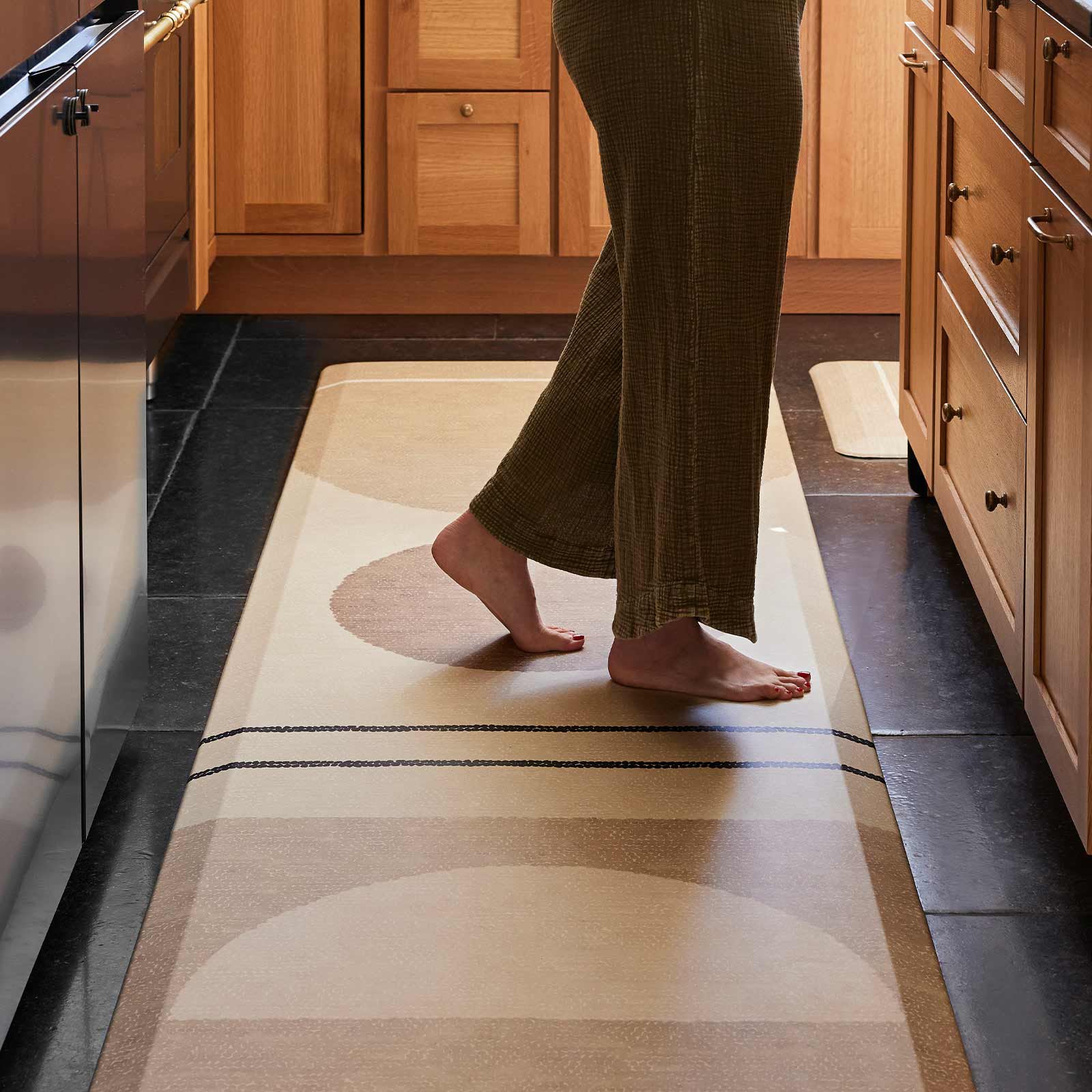 Geode Sesame neutral geometric print standing mat in size 30x108 showing woman's standing on the mat in front of a kitchen counter