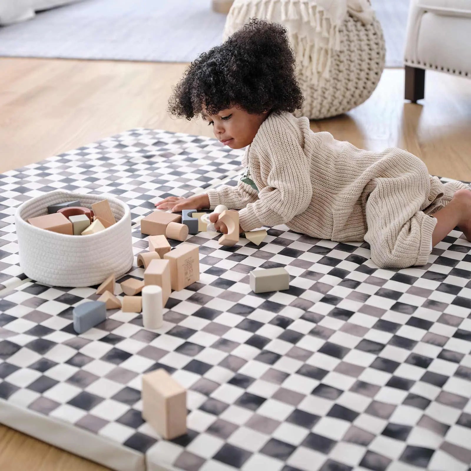 Tuxedo black and white checker print tumbling mat with toddler laying on the mat playing with wooden blocks