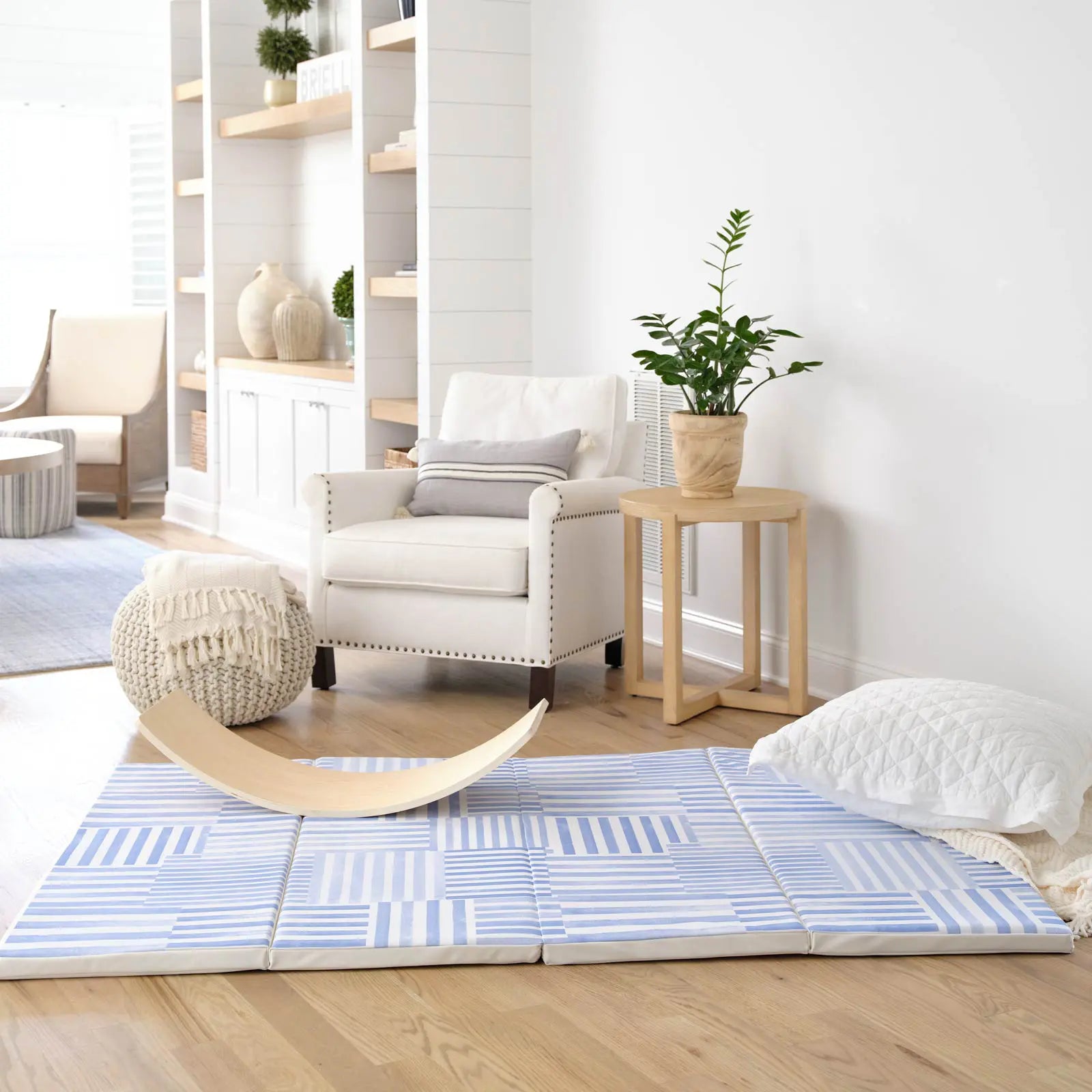 French blue and white inverted stripe tumbling mat shown in a lviing room with balance board and pillow on the mat