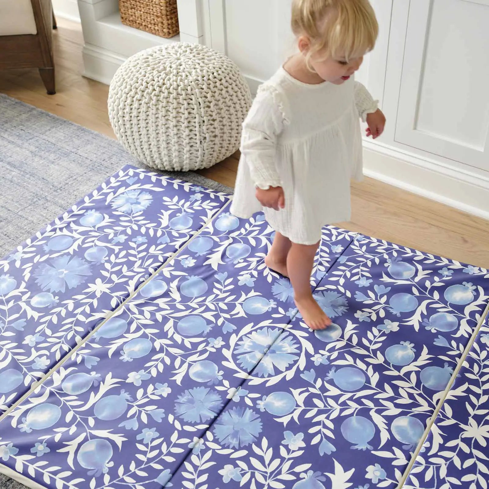 Deep sea blue and white floral tumbling mat shown in living room with toddler girl walking across the mat