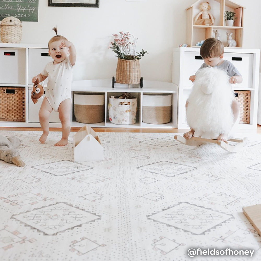 Neutral boho print baby play mat shown in play room with two babies playing on play mat. @fieldsofhoney written in bottom right hand corner.
