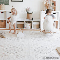 Neutral boho print baby play mat shown in play room with two babies playing on play mat. @fieldsofhoney written in bottom right hand corner.