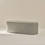 Rectangular ottoman with a ribbed texture on a neutral background