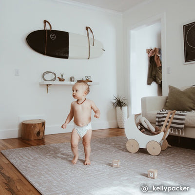 Beige neutral boho print baby play mat shown in living room with baby playing with wagon and toys.