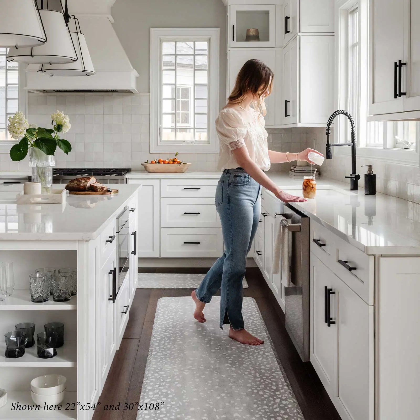 Fawn silver gray animal print kitchen mat shown in sizes 22x54 and 30x108 with woman standing on size 30x108 making a smoothie