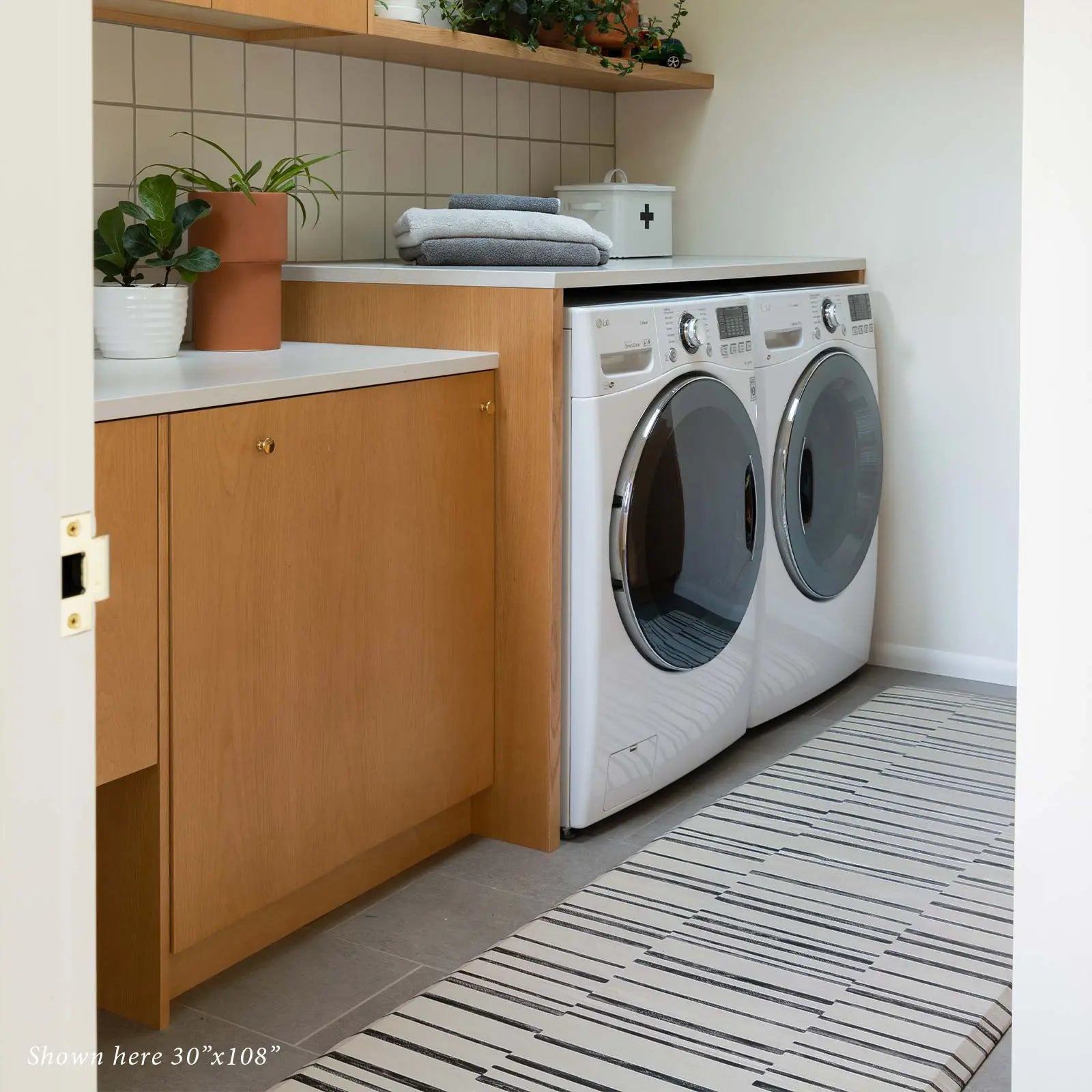 Black and white inverted stripe standing mat in a laundry room in front of washer dryer in size 30x108