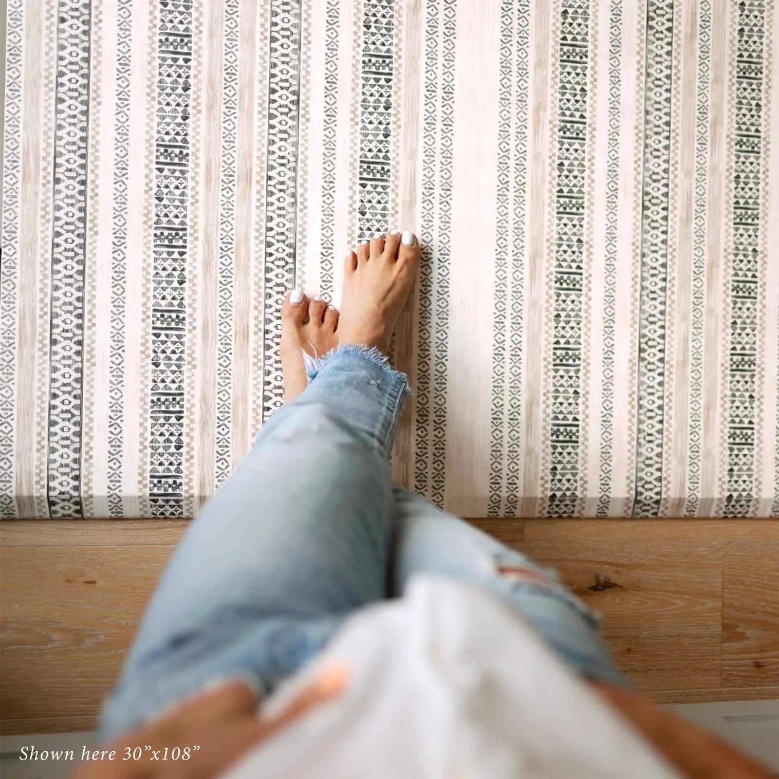 Tan and black neutral boho stripe kitchen mat with woman's feet standing on size 30x108
