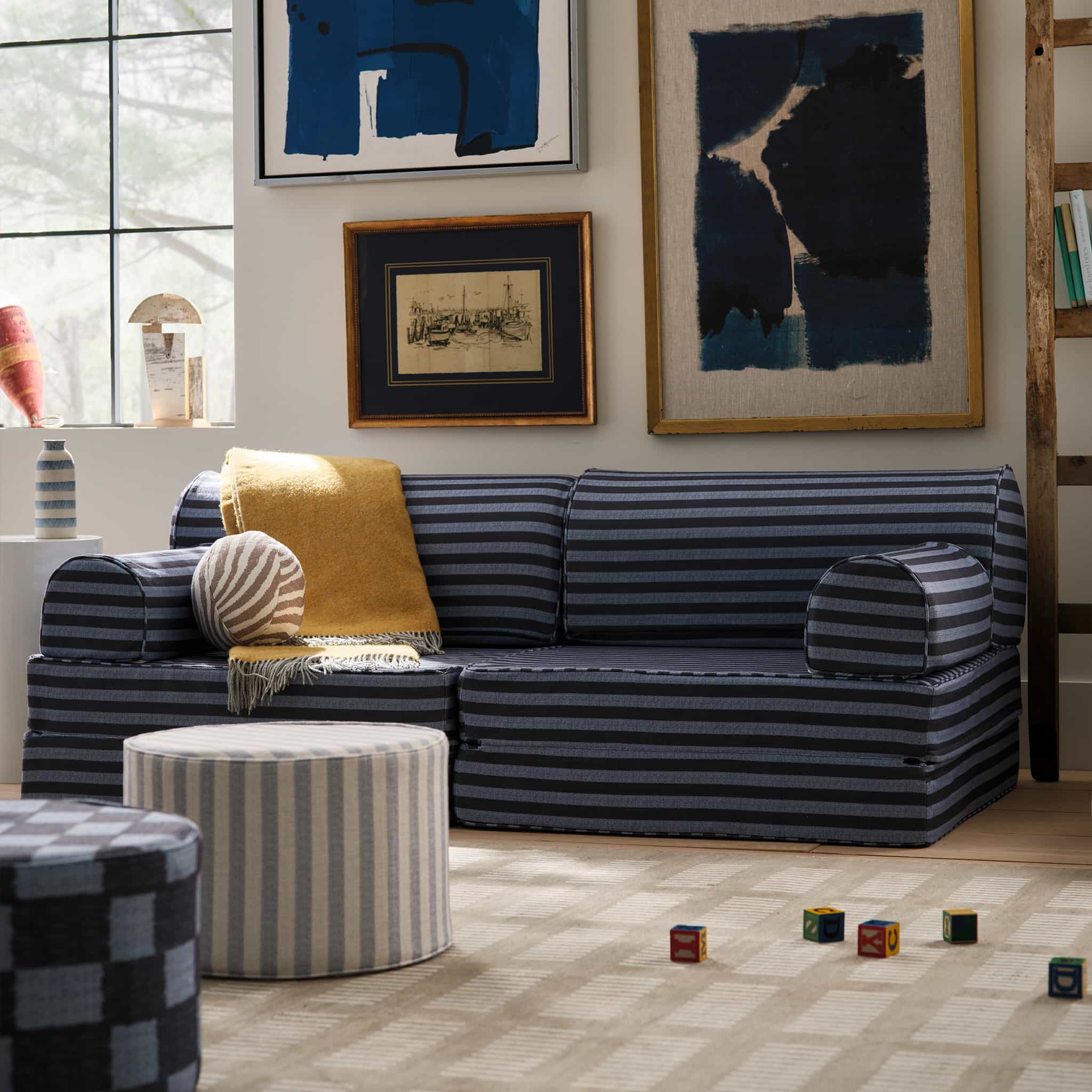 Blue striped play couch against a wall shown with other blue cushions and toy blocks on the floor