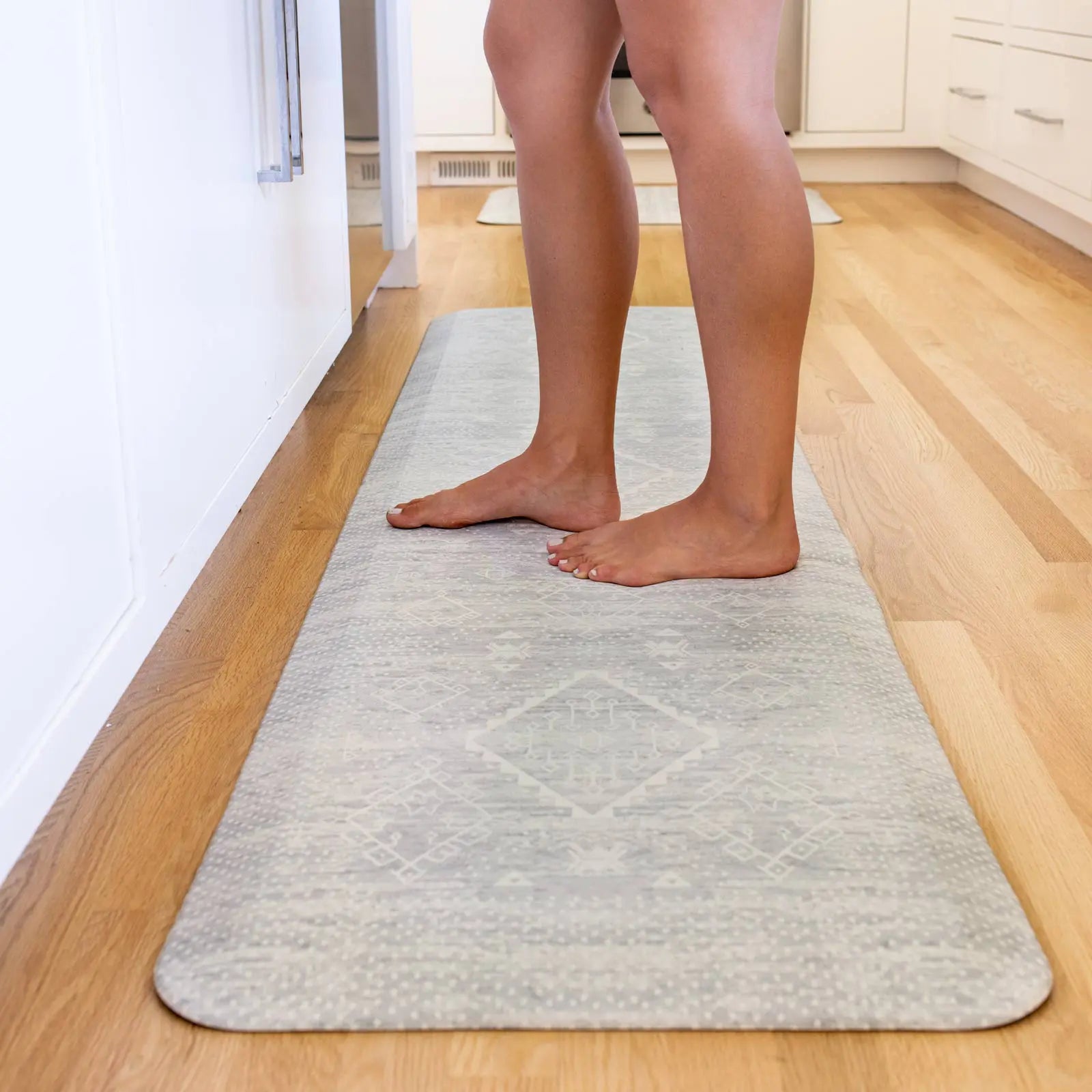 Ula gray and white Minimal Boho Pattern Standing Mat shown in kitchen with woman standing in size 22x72