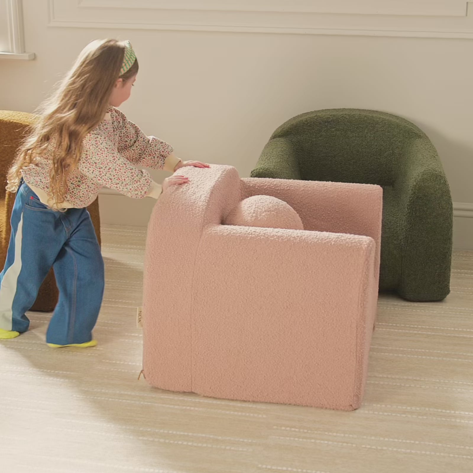Children move around solid color boucle fabric play chairs and pillows in a play room