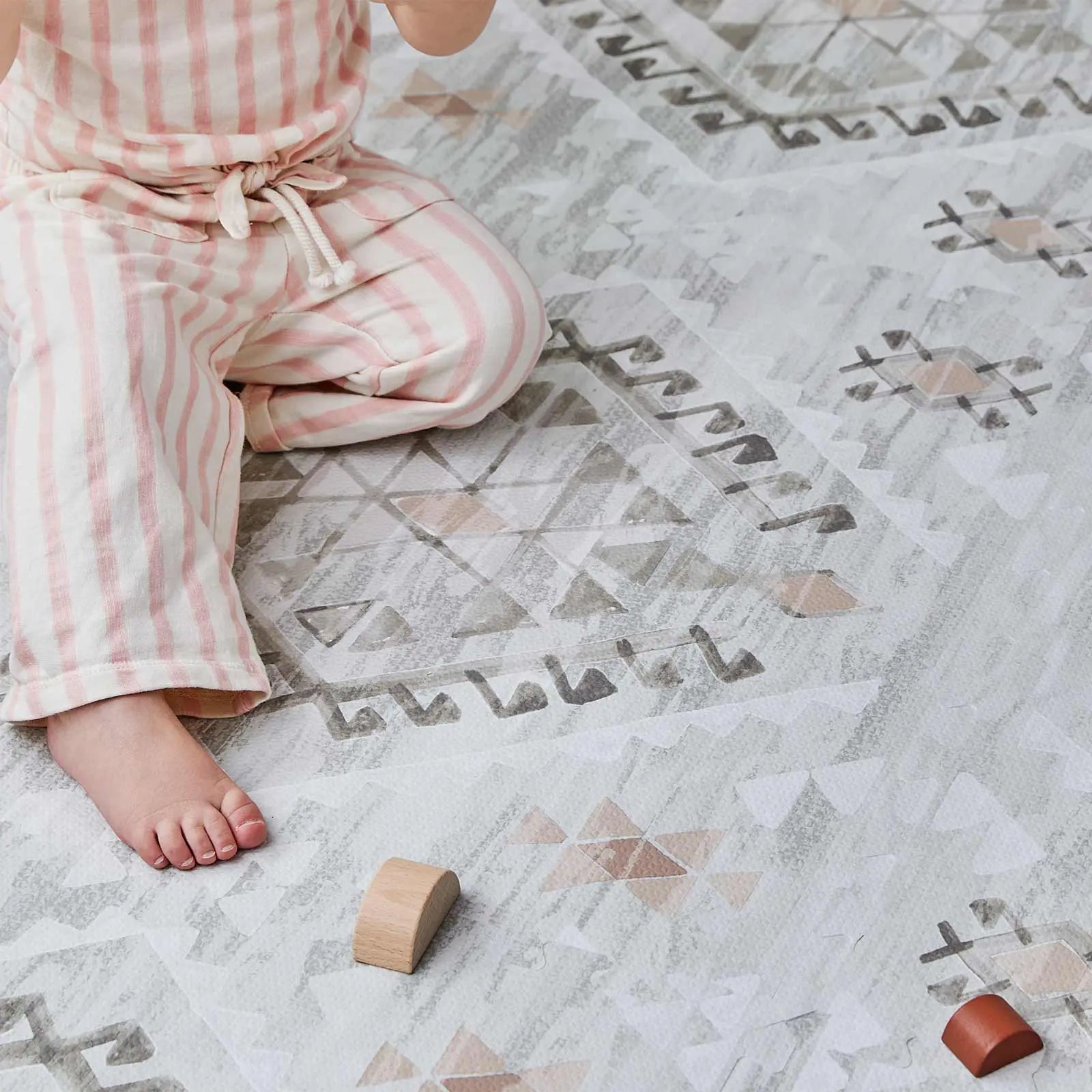 Nalla Basalt grey and sage green boho print play mat close up shot show toddler girl sitting on the mat and wooden blocks
