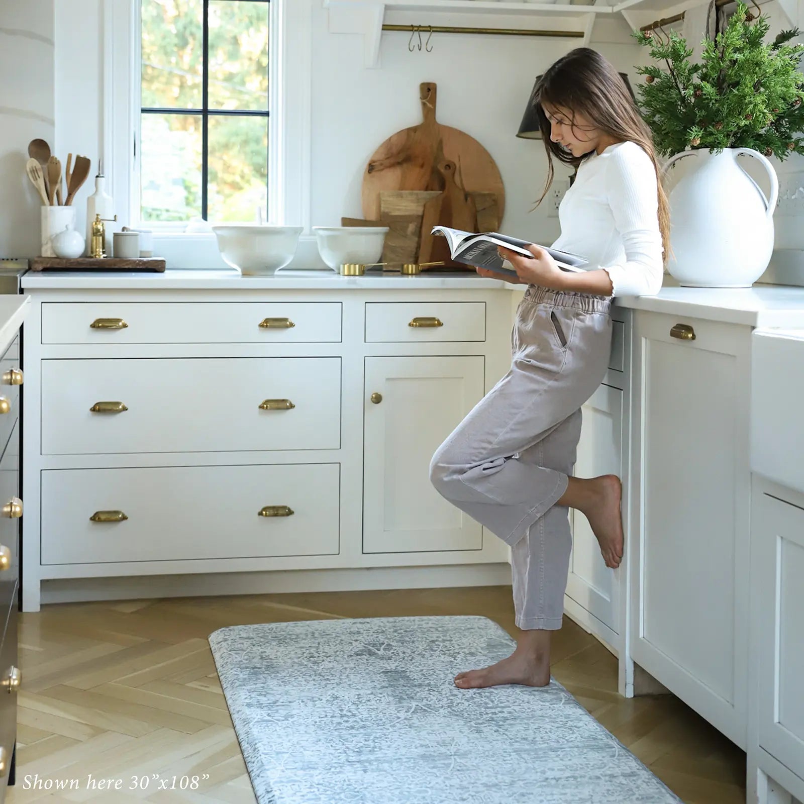 Gray neutral boho print kitchen mat shown with woman reading in kitchen on size 30x108