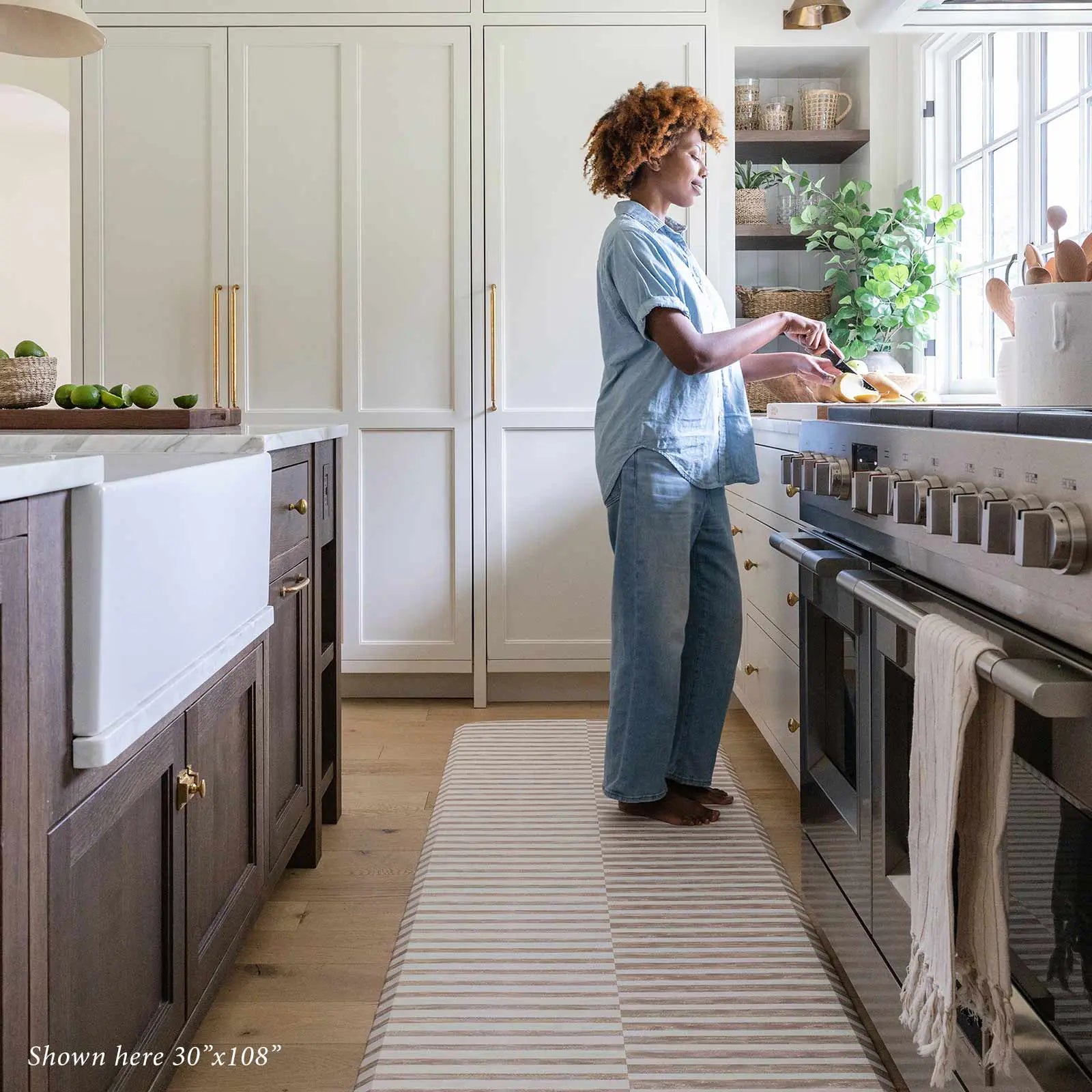 Reese chai beige and white inverted stripe standing mat shown in kitchen with woman cooking in size 30x108