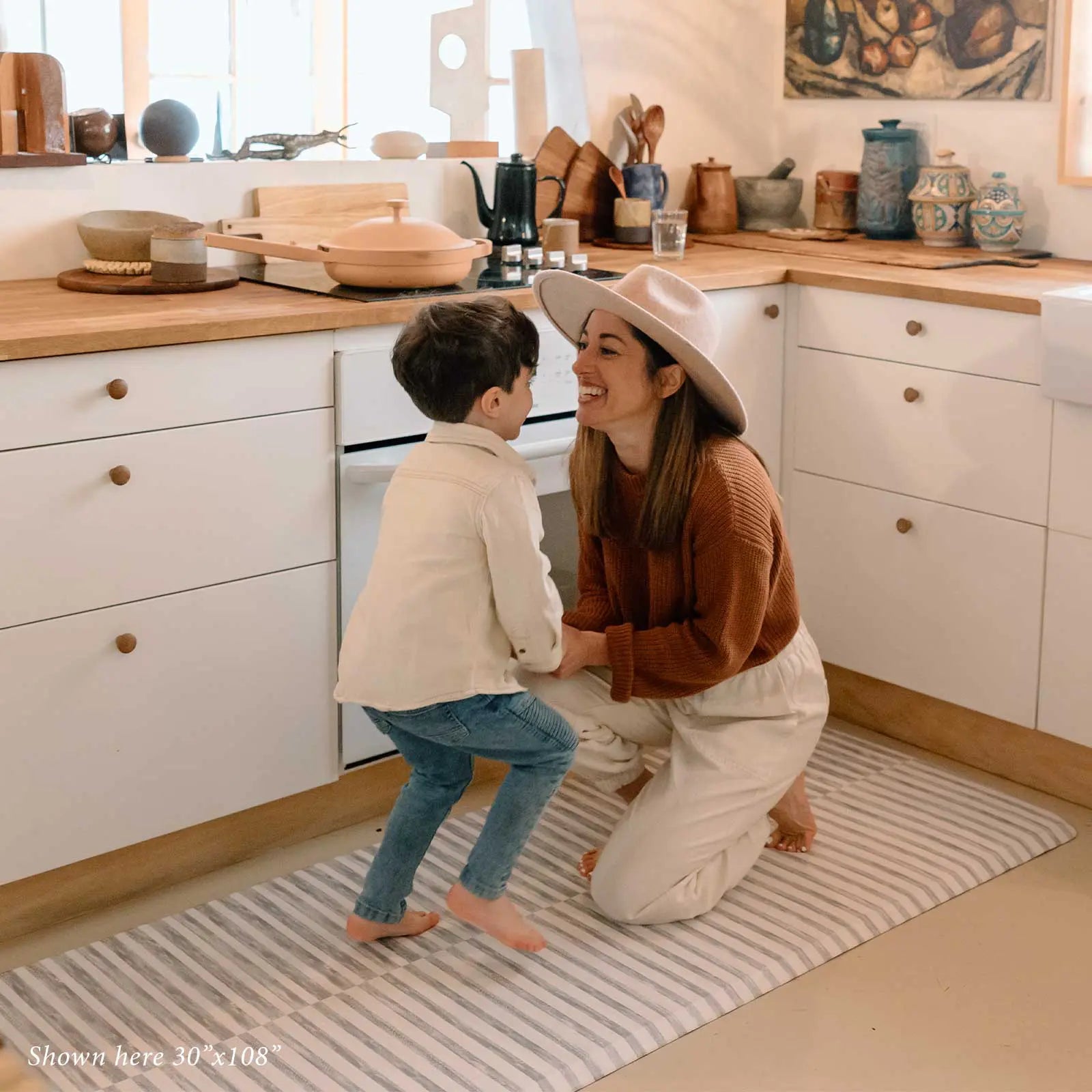 Reese pewter gray and white inverted stripe standing mat shown in kitchen in size 30x108 with Mom and son laughing