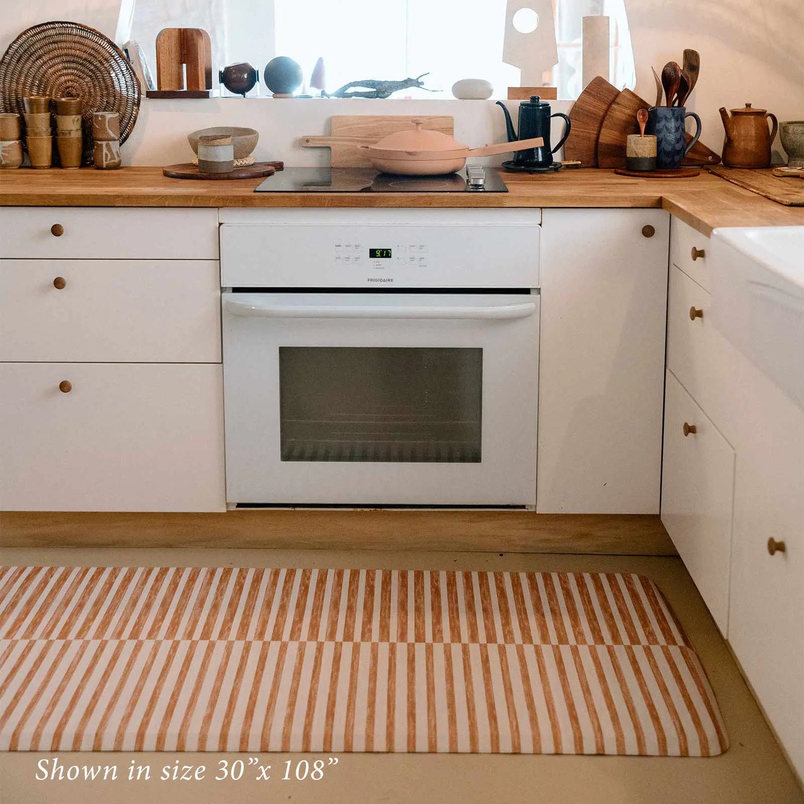 Reese terracotta brown and white inverted stripe standing mat shown in kitchen in size 30x108