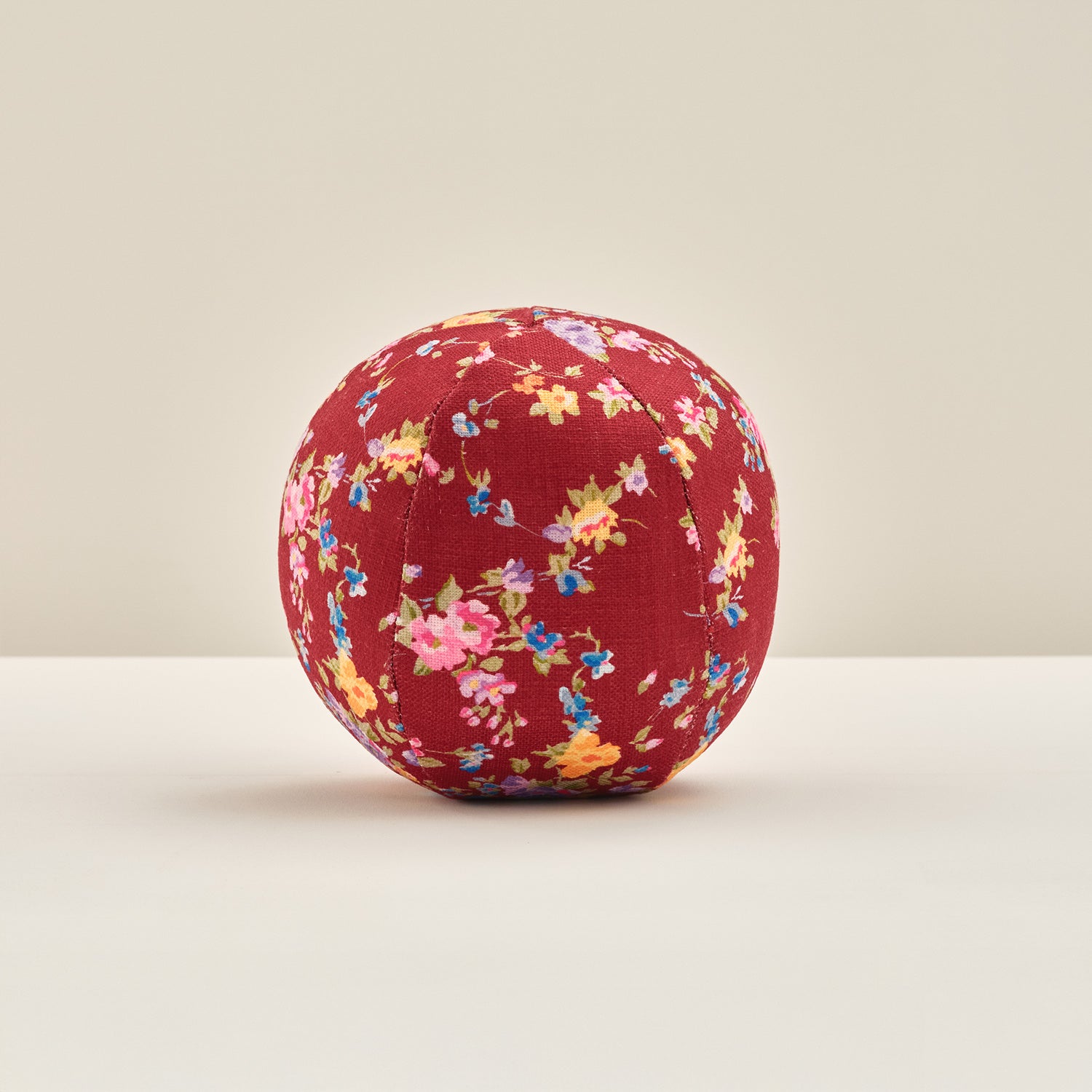 Floral-patterned ball pillow on a beige background