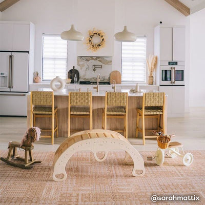 Honey mustard yellow boho print baby play mat shown in living room with wooden play arch, rocking horse, and tricycle.