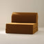 A brown upholstered play couch with a beige background 