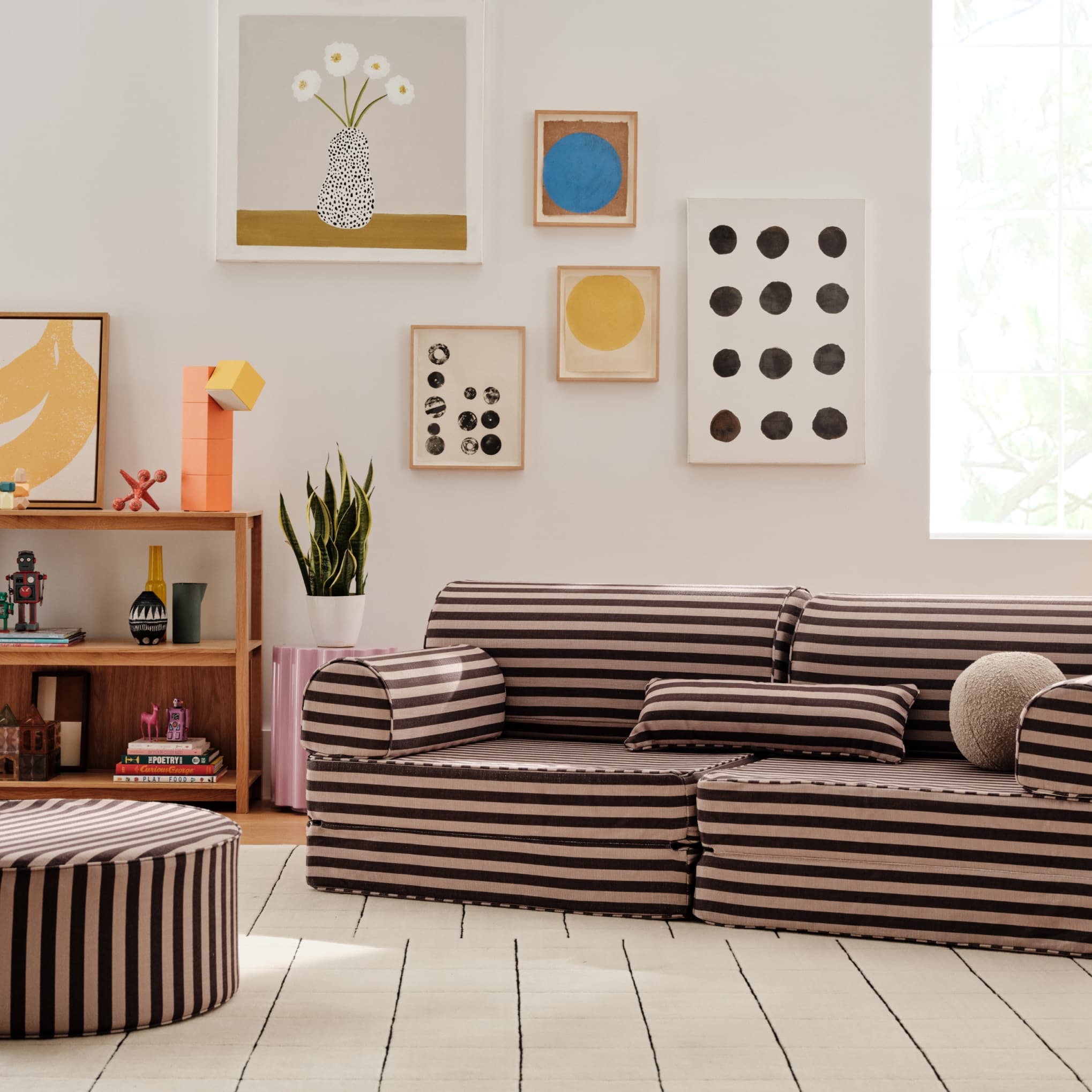 Living room with a striped sofa, bookshelf, and wall art