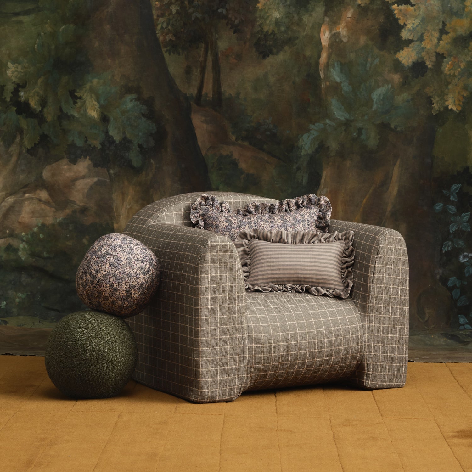 Gray checkered armchair with decorative pillows in a room with a forest mural.