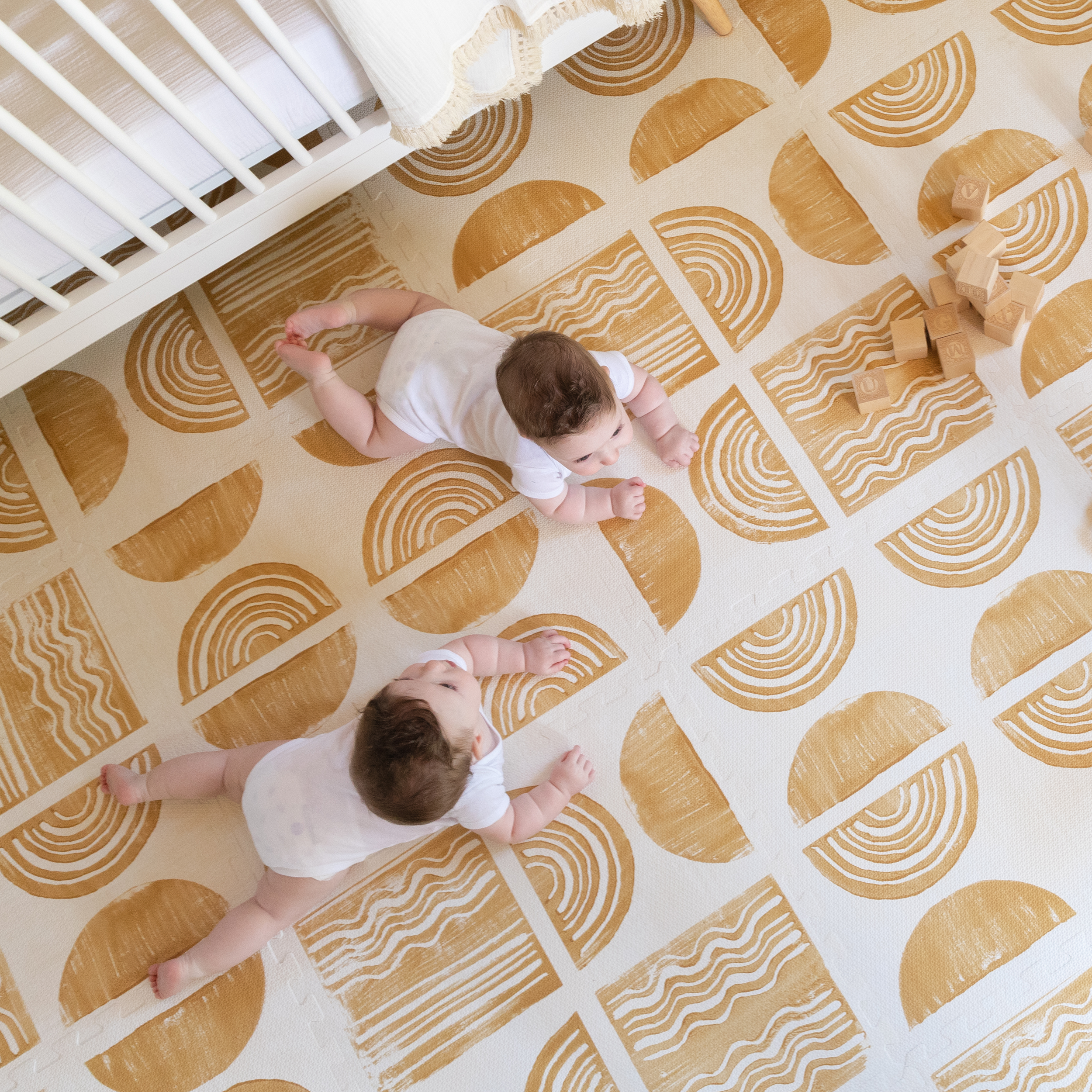 Ada modern minimalist baby play mat in Sunflower, mustard yellow and off white. Photo shot from above in a nursery with twin babies playing on the mat.
