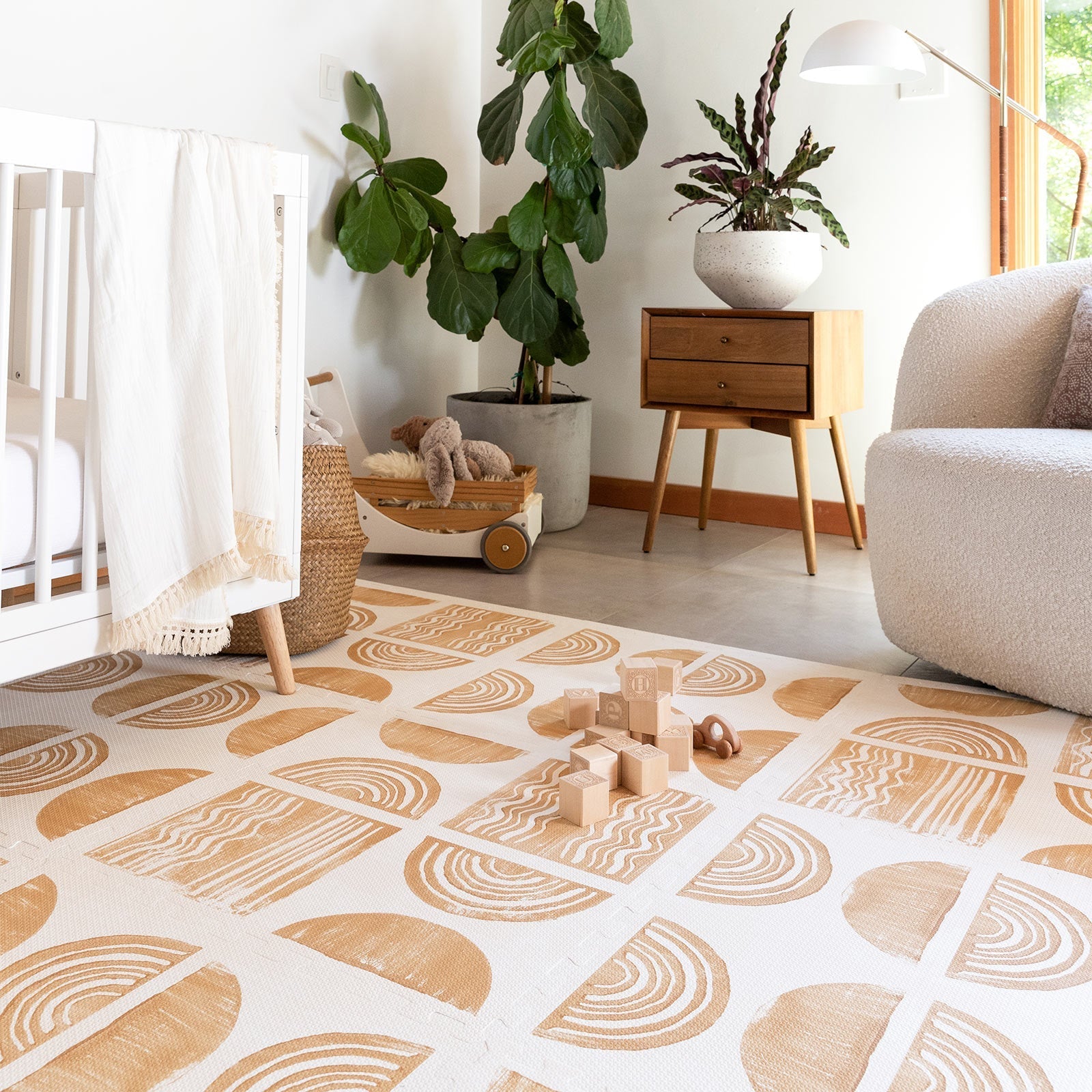 Ada modern minimalist baby play mat in Sunflower, mustard yellow and off white. Shown in a nursery with crib, toys, chair, and plant.