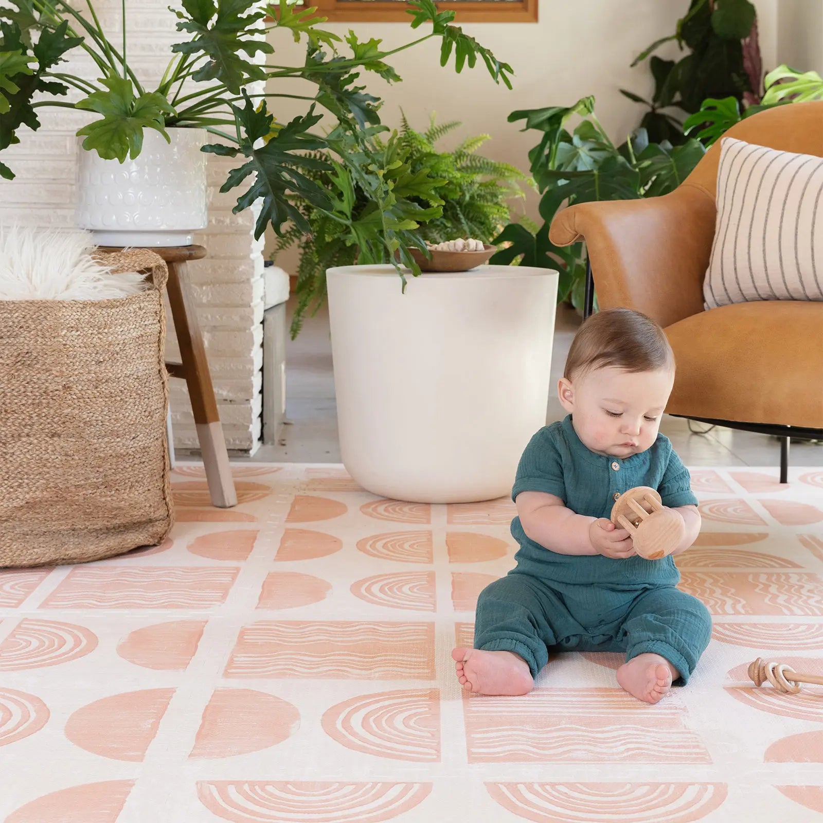 Ada melon pink and off white block print baby play mat. Shown in living room baby playing with toys.