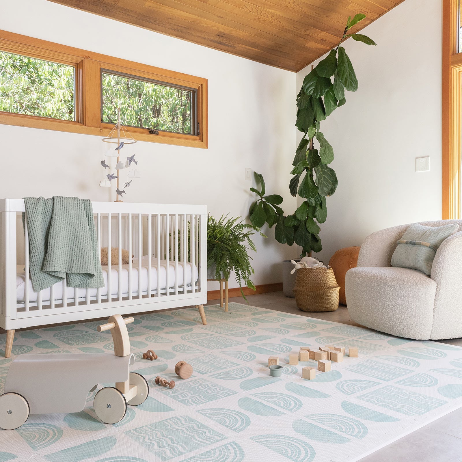 Ada modern minimalist baby play mat in Celadon, pale aqua blue and off white. Shown in nursery with crib, toys, chair, and plants.