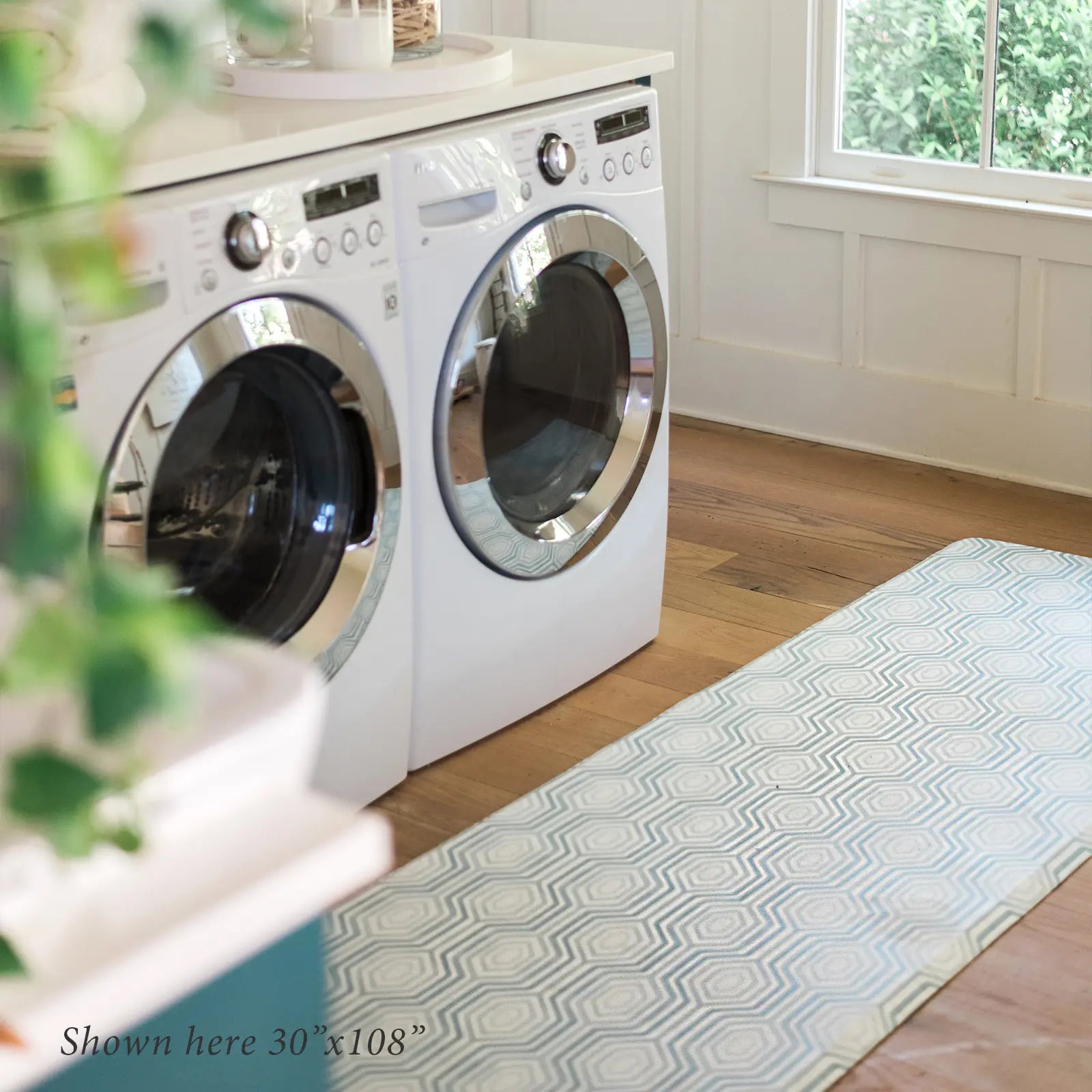 Blake waves blue and white mod preppy geometric print kitchen mat shown in size 30x108 in front of washer and dryer in laundry room.