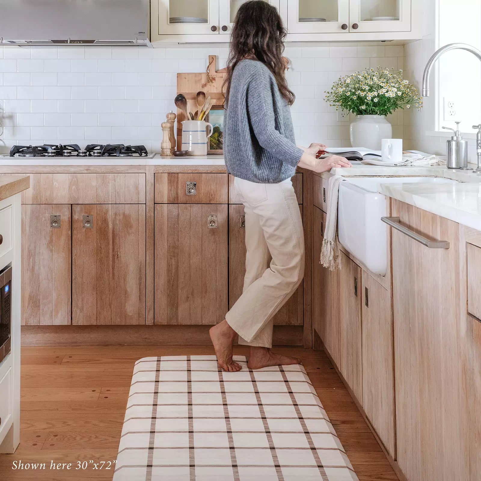 Windowpane Neutral Grid Pattern Standing Mat shown in kitchen with woman reading cookbook