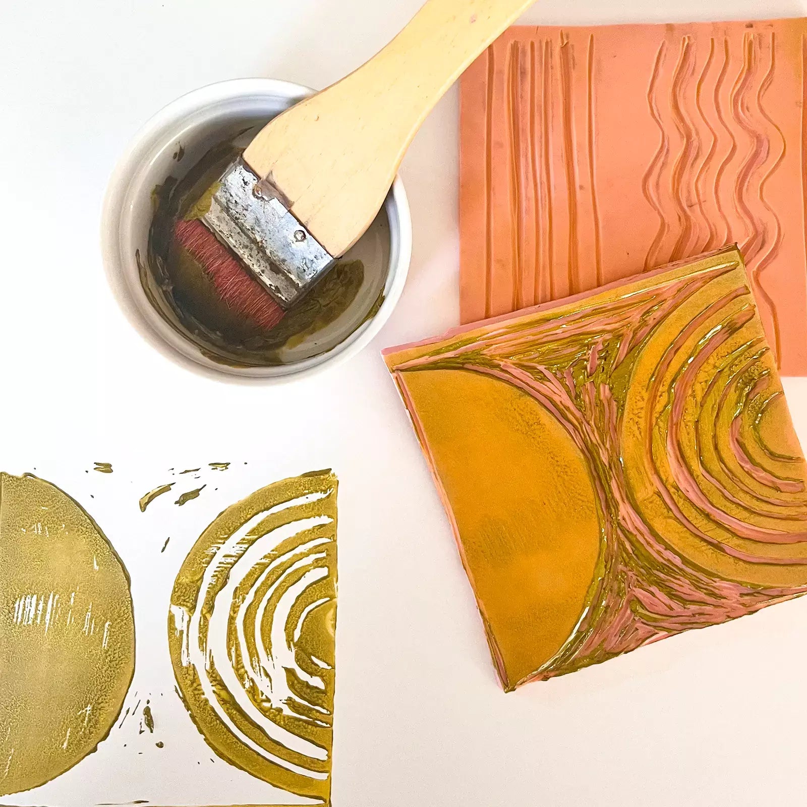 Close up shot of a paint brush, paint, and wood pattern block used to create the original block print illustration of the Ada Play Mat.