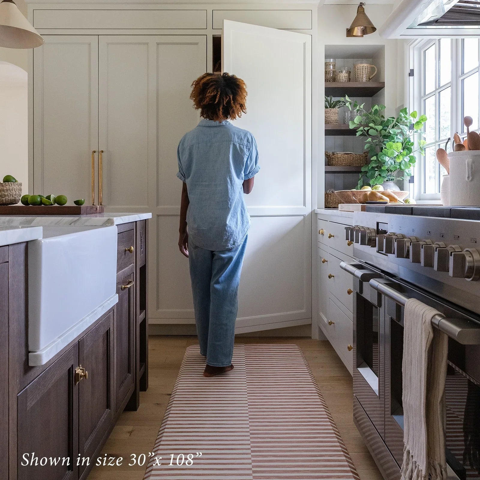 Reese terracotta brown and white inverted stripe standing mat shown in kitchen in size 30x108 with woman opening pantry