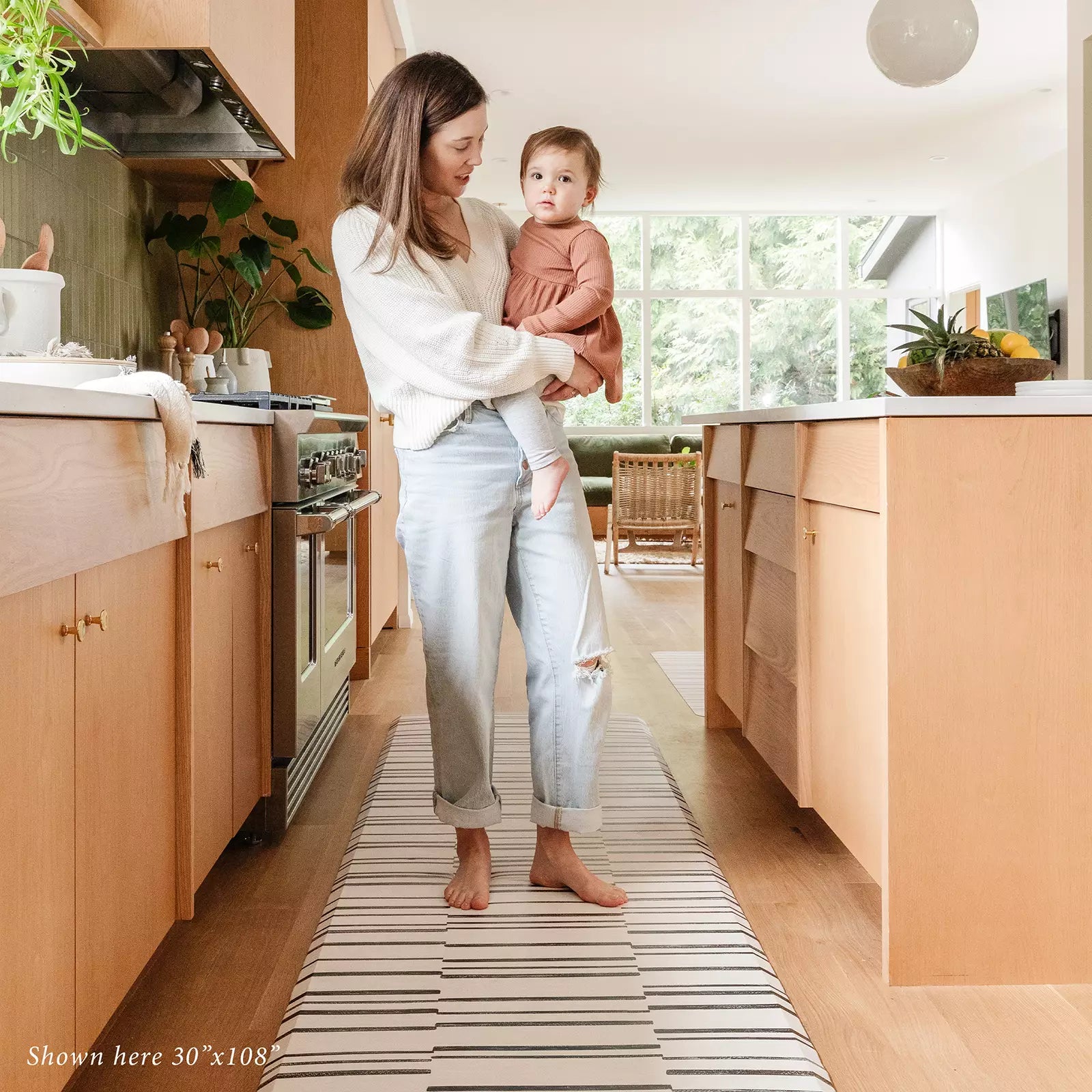 Black and white inverted stripe kitchen mat in kitchen with Mom holding a baby standing on size 30x108.