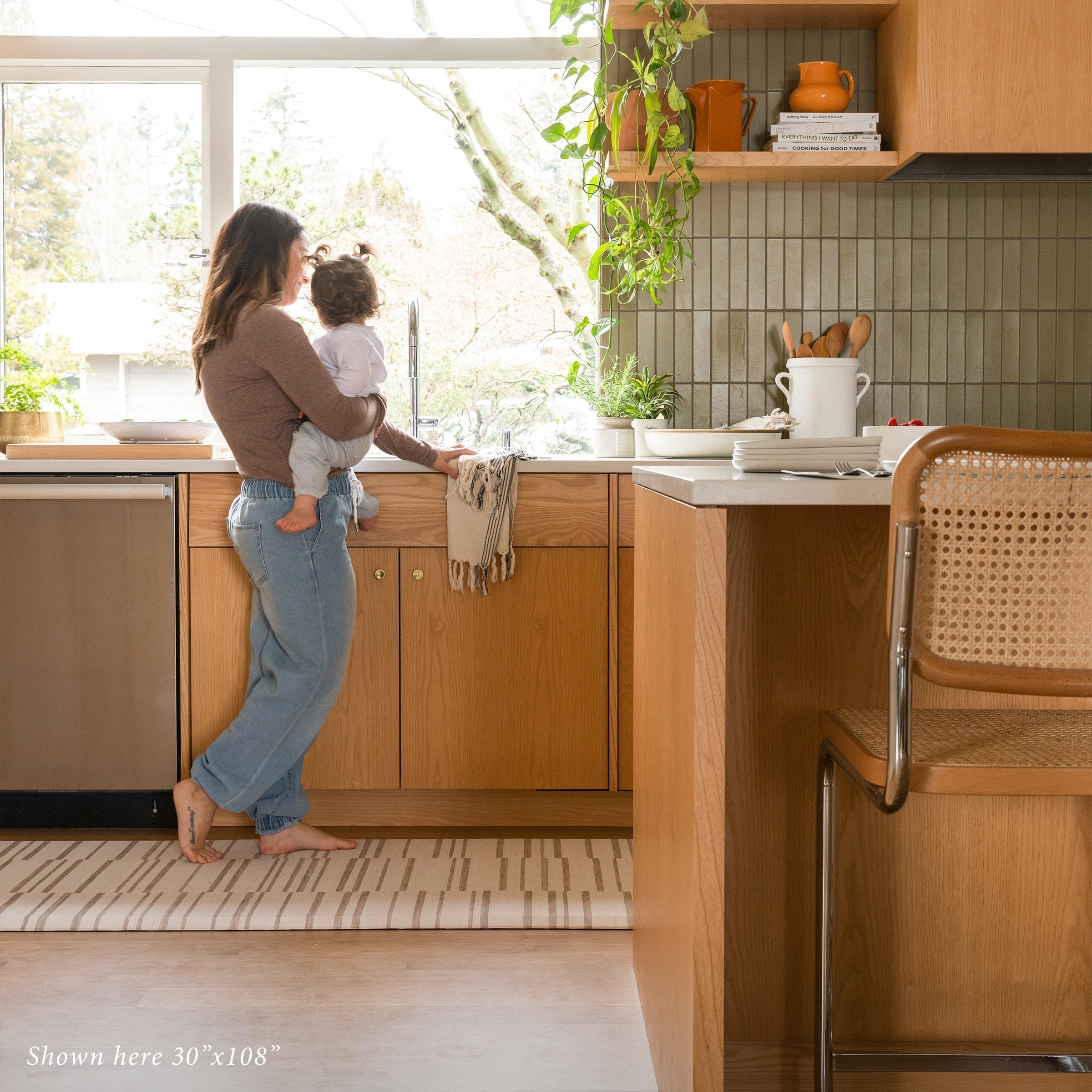 Beige inverted stripe kitchen mat in kitchen with Mom holding a baby on size 30x108.